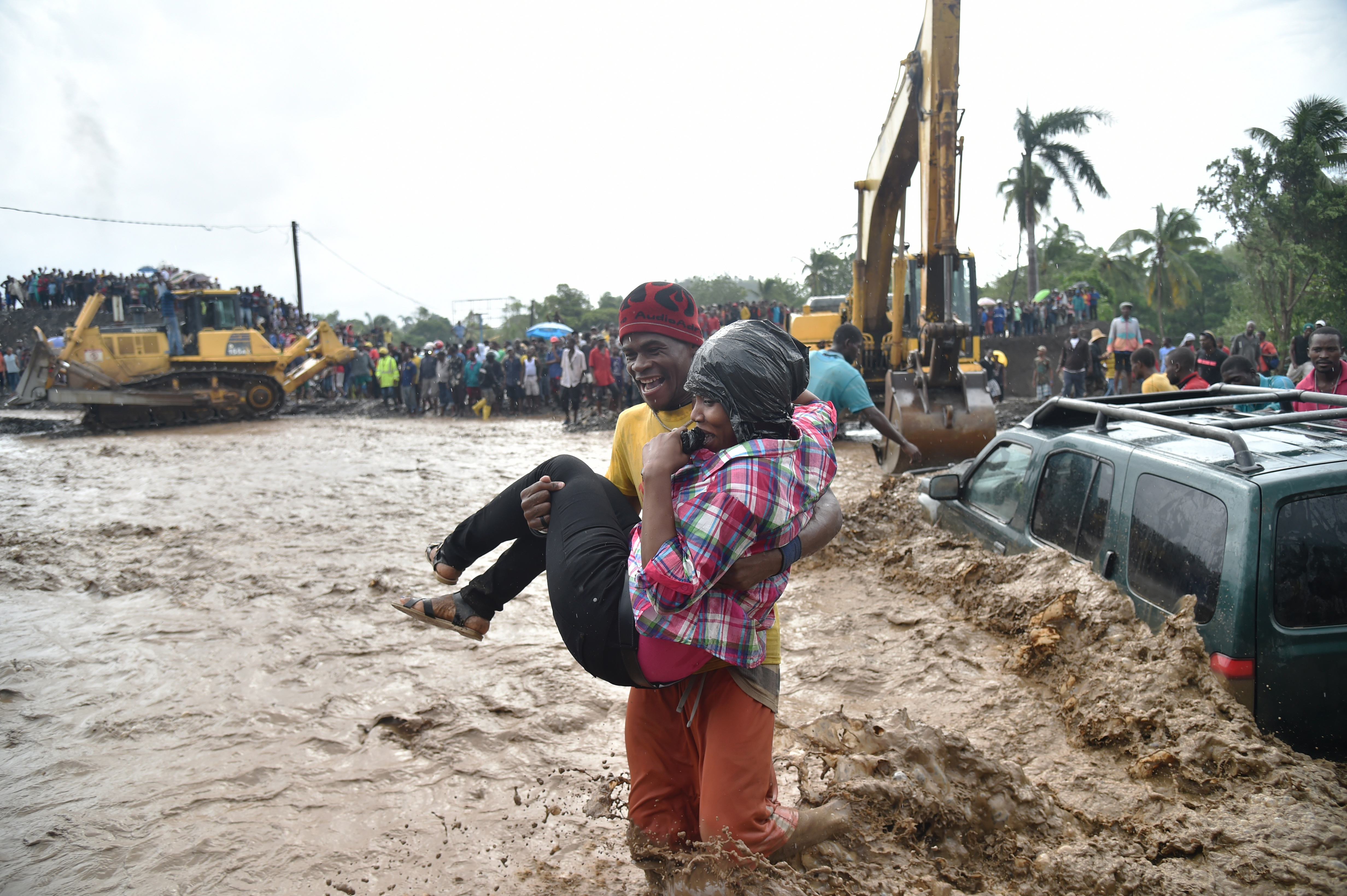 A woman is carried across the river La Digue in Petit Goave where the bridge collapsed during the rains of the Hurricane Matthew, southwest of Port-au-Prince, October 5, 2016. Haiti and the eastern tip of Cuba -- blasted by Matthew on October 4, 2016 -- began the messy and probably grim task of assessing the storm's toll. Matthew hit them as a Category Four hurricane but has since been downgraded to three, on a scale of five, by the US National Hurricane Center. / AFP PHOTO / HECTOR RETAMAL