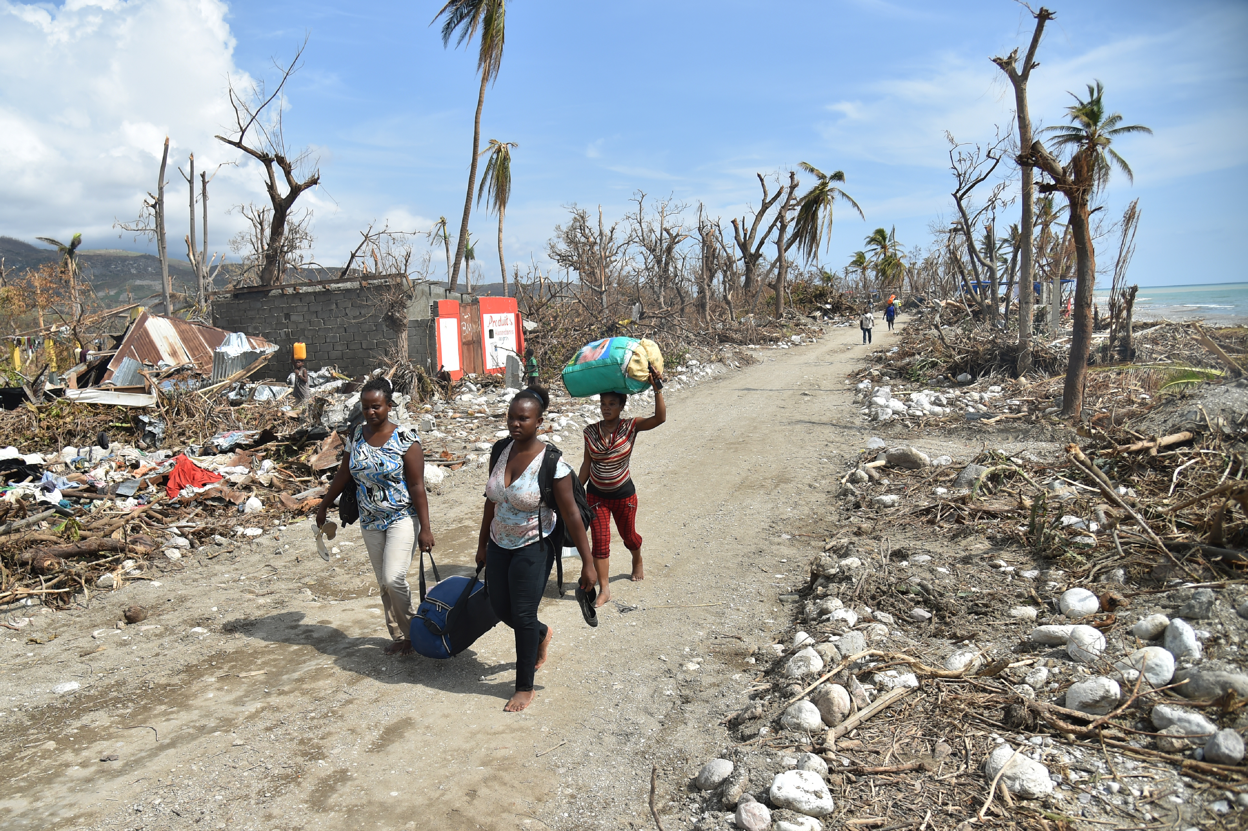 People walk in a street of Les Cayes, Haiti on October 10, 2016, following the passage of Hurricane Matthew.  Haiti faces a humanitarian crisis that requires a "massive response" from the international community, the United Nations chief said , with at least 1.4 million people needing emergency aid following last week's battering by Hurricane Matthew. / AFP PHOTO / HECTOR RETAMAL
