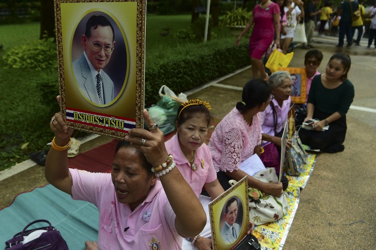 Women hold portraits of Thai King Bhumibol Adulyadej as they pray for his health at Siriraj Hospital, where the king is being treated, in Bangkok on October 12, 2016. Security outside the hospital where Thailand's ailing monarch is being treated was stepped up on Wednesday before a planned visit by his son, a hospital official said, following unprecedented concern over the king's health. / AFP PHOTO / MUNIR UZ ZAMAN