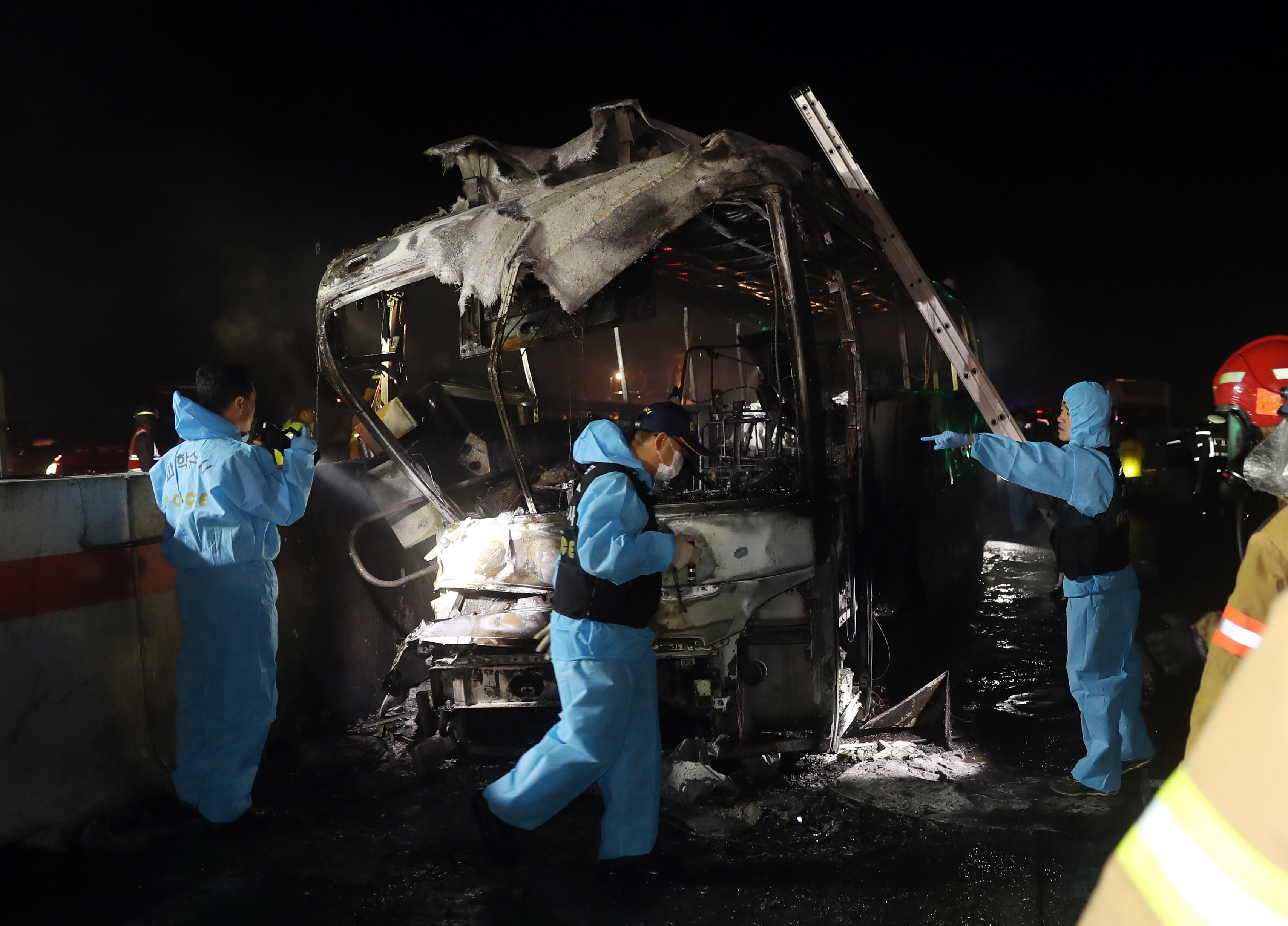 Fire and rescue services attend the scene of a bus accident near Ulsan, on South Korea's south-eastern coast on October 14, 2016. At least 10 people were killed and seven others seriously injured as their tour bus caught fire on a highway near South Korea's southeastern city of Ulsan, police said. The bus was carrying 20 people late October 13 night when one of the front tires exploded, causing it to crash into a concrete guardrail and catch fire, South Korea's Yonhap news agency reported citing a witness of the fatal accident. / AFP PHOTO / YONHAP / Yonhap / - South Korea OUT / REPUBLIC OF KOREA OUT NO ARCHIVES RESTRICTED TO SUBSCRIPTION USE