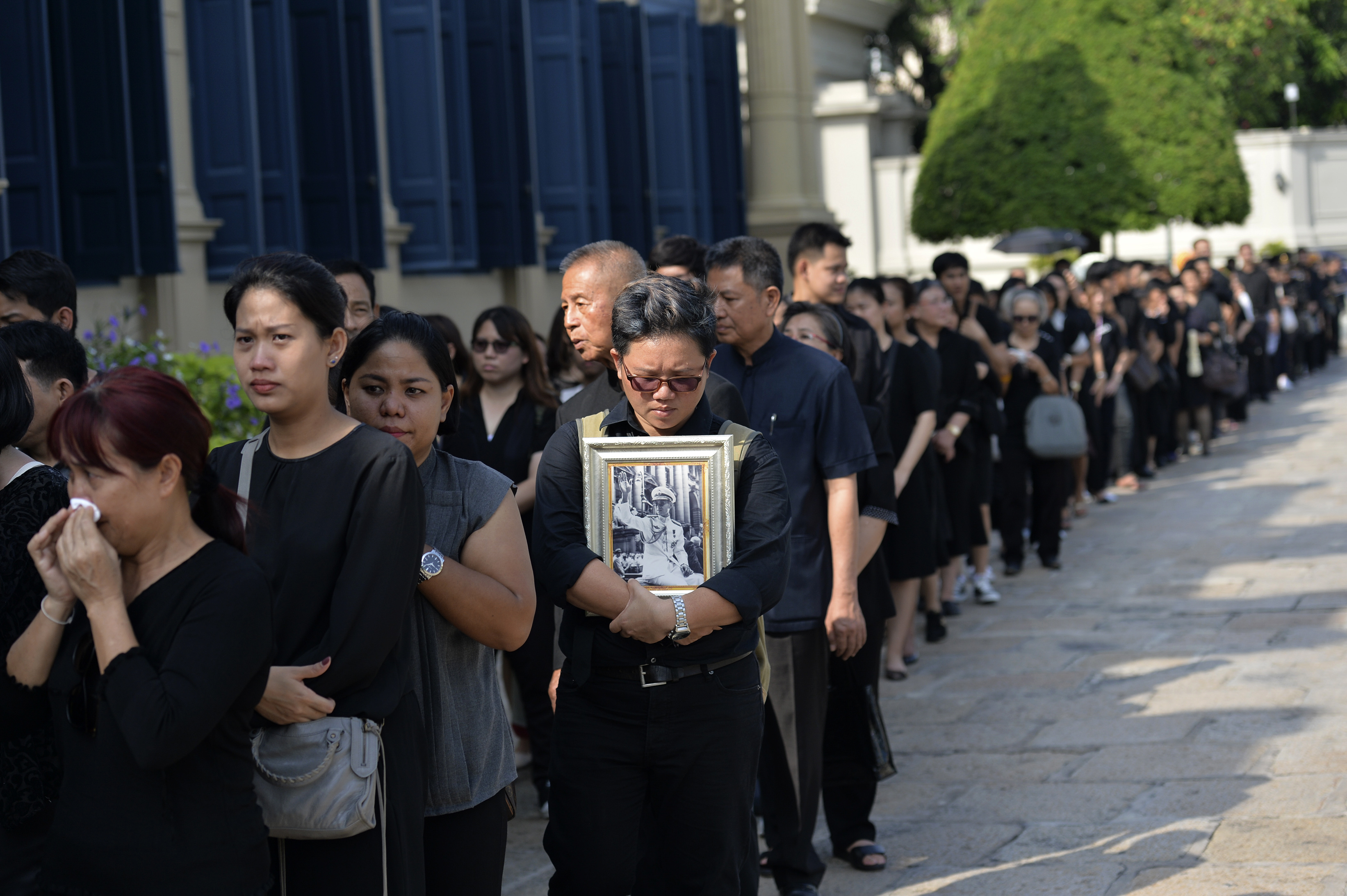 People wait in line to pay their respects to Thai King Bhumibol Adulyadej at the Grand Palace in Bangkok on October 14, 2016. King Bhumibol Adulyadej, long a unifying figure in politically fractious Thailand, died on October 13 and uncertainty over the succession quickly arose as his crown prince reportedly sought a delay in taking over. / AFP PHOTO / MUNIR UZ ZAMAN
