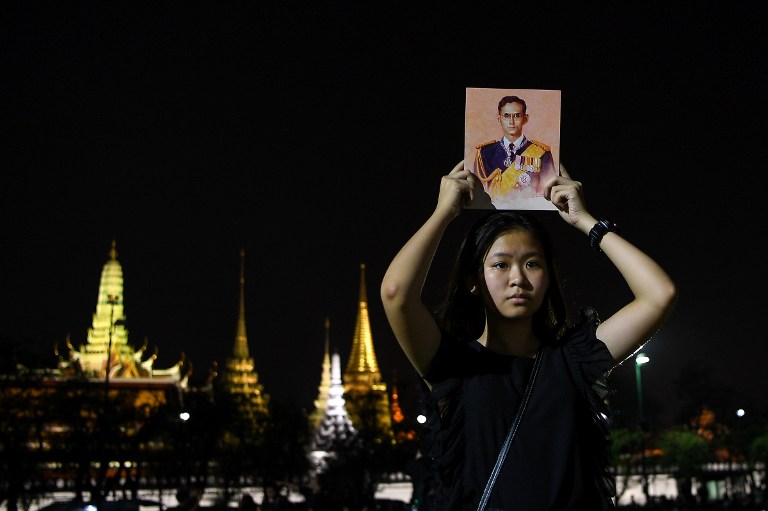A woman holds a portrait of the late Thai King Bhumibol Adulyadej outside the Grand Palace in Bangkok on October 15, 2016. / AFP PHOTO / MANAN VATSYAYANA