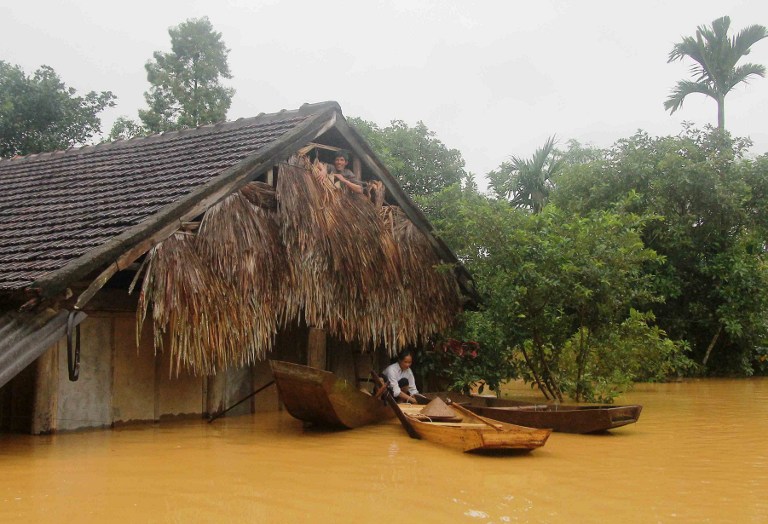 A Vietnamese villager sits on a boat next to his flooded home in Huong Khe district in the central province of Ha Tinh on October 15, 2016. At least 11 people have died with several more missing in heavy flooding in central Vietnam, state media said on October 15, 2016, with tens of thounsands of homes completely submerged by water. / AFP PHOTO / VIETNAM NEWS AGENCY