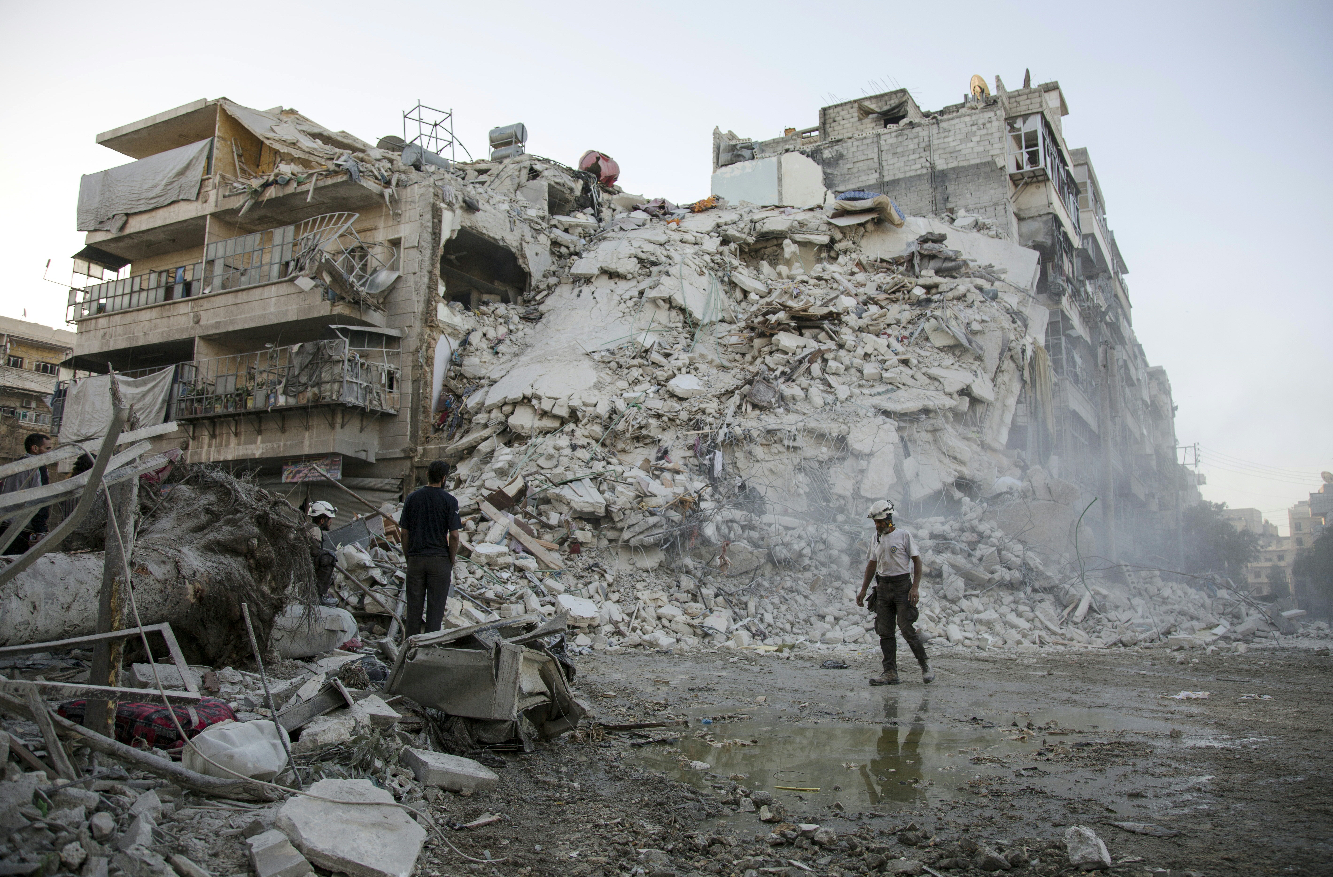 Members of the Syrian Civil Defence, known as the White Helmets, search for victims amid the rubble of a destroyed building following reported air strikes in the rebel-held Qatarji neighbourhood of the northern city of Aleppo, on October 17, 2016.  Dozens of civilians were killed as air strikes hammered rebel-held parts of Aleppo early morning, despite Western warnings of potential sanctions against Syria and Russia over attacks on the city. Both Russian and Syrian warplanes are carrying out air strikes over Aleppo in support of a major offensive by regime forces to capture rebel-held parts of the northern city.  / AFP PHOTO / KARAM AL-MASRI