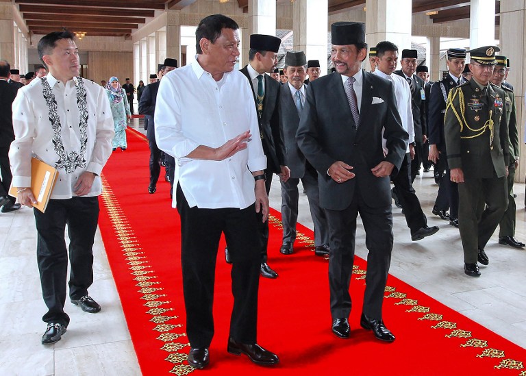This handout photo released on October 17, 2016 by the Brunei Informations Department shows Brunei's Sultan Hassanal Bolkiah (R) and Philippiness President Rodrigo Duterte  (2nd L) walking together during Duterte's official welcoming ceremony at the Istana Nurul Iman in Brunei.  Duterte arrived in Brunei for a three-day official visit and will hold talks with Sultan Bolkiah on bilateral and international issues. / AFP PHOTO / Brunei Informations Department / STR / 