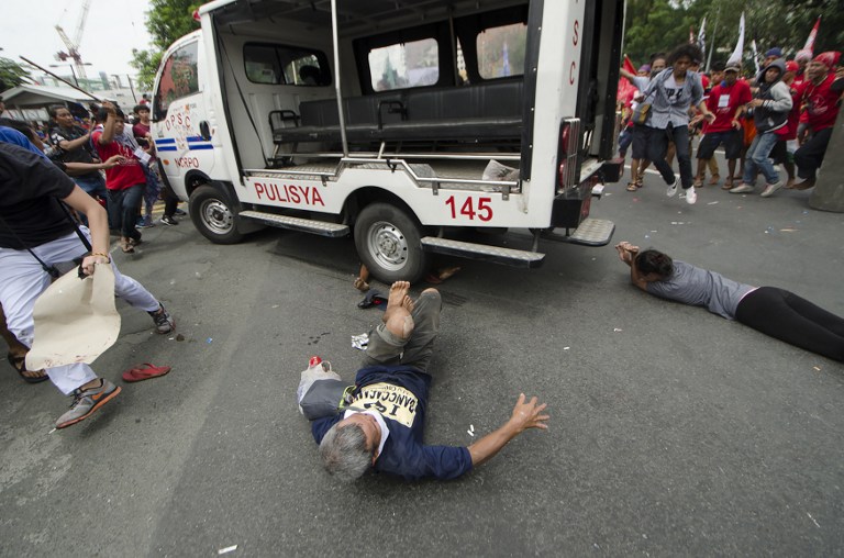 Protesters lie on the ground after being hit by a police van during a rally in front of the US embassy in Manila on October 19, 2016.  A Philippine police van on October 19 rammed and ran over baton-wielding protesters outside the US embassy in Manila. / AFP PHOTO / Rob Reyes