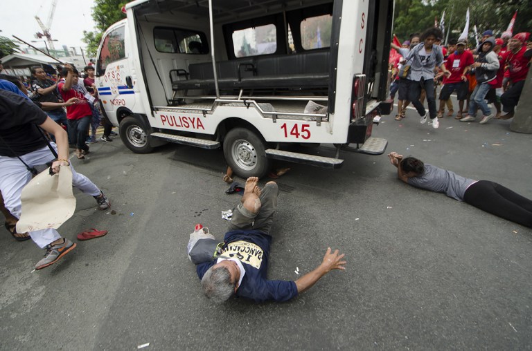 Protesters lie on the ground after being hit by a police van during a rally in front of the US embassy in Manila on October 19, 2016. A Philippine police van on October 19 rammed and ran over baton-wielding protesters outside the US embassy in Manila. / AFP PHOTO / Rob Reyes