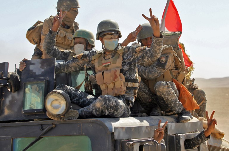 Iraqi government forces flash the sign for victory as they advance towards the village of Tal al-Shawk on the eastern bank of the Tigris river on October 20, 2016, during the ongoing operation to retake Mosul from the Islamic State (IS) group. The operation is Iraq's biggest in years and aims to wrest back Mosul, the country's second city and the last major IS stronghold in Iraq. / AFP PHOTO / AHMAD AL-RUBAYE
