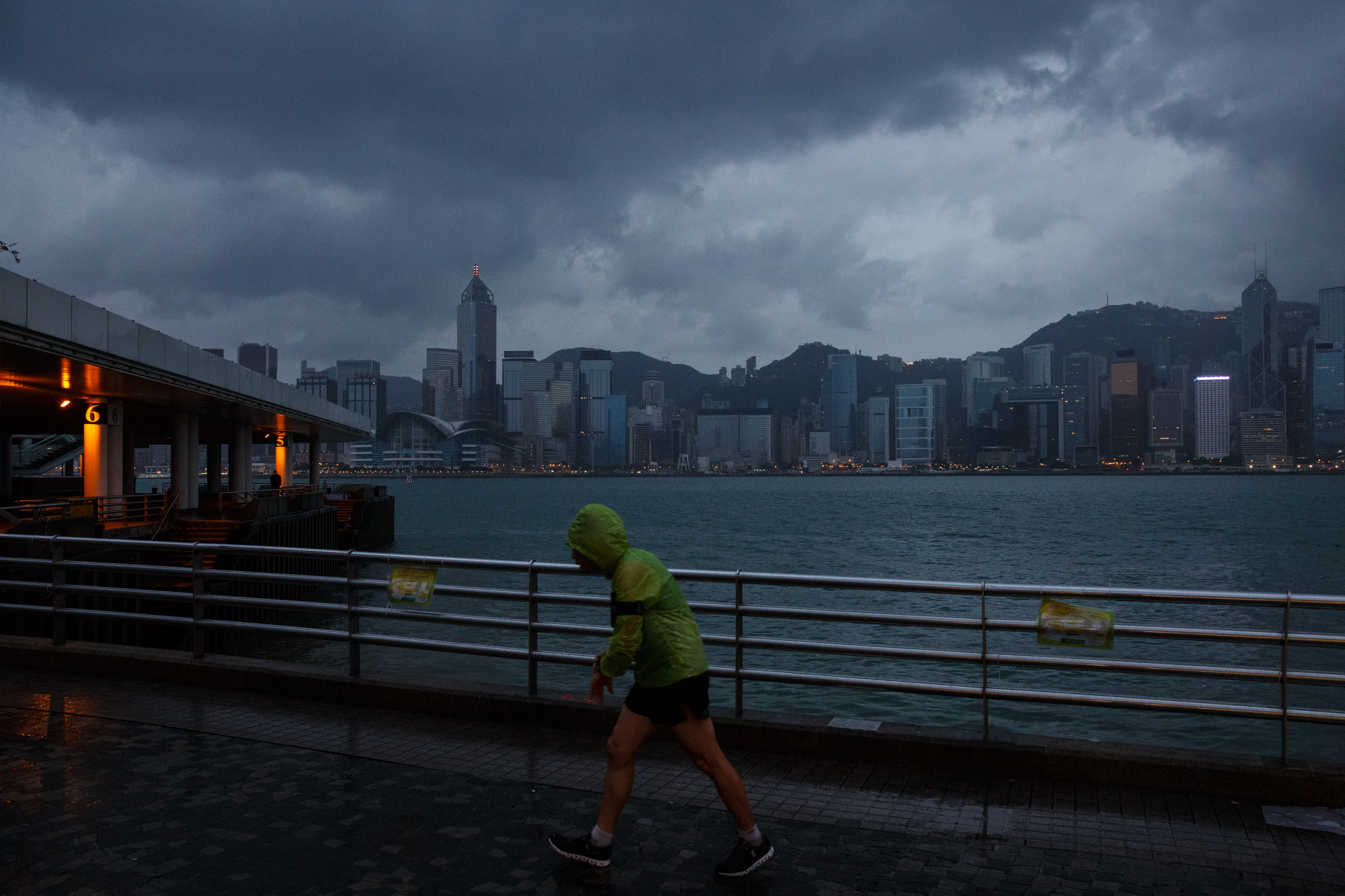 A man jogs along a promenade running along Victoria Harbour as Typhoon Haima approaches Hong Kong early on October 21, 2016, shortly after the typhoon signal eight warning was raised. Typhoon Haima approached Hong Kong on October 21 after killing at least four in the Philippines. / AFP PHOTO / Anthony WALLACE