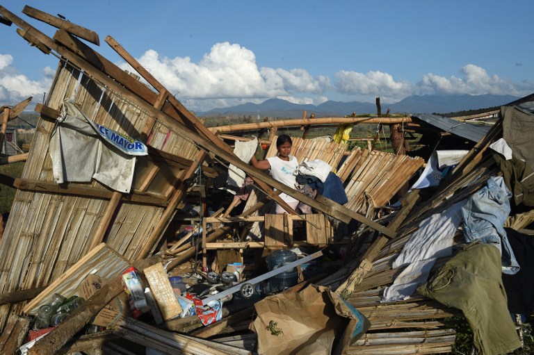 A resident removes dried clothes amongst the ruins of their house destroyed at the height of typhoon Haima in Cabagan town, Isabela province, north of Manila on October 21, 2016. Hungry Philippine typhoon survivors huddled in makeshift shelters and waited for aid on October 21, after losing nearly everything from one of the most powerful storms to hit the Southeast Asian archipelago. / AFP PHOTO / TED ALJIBE