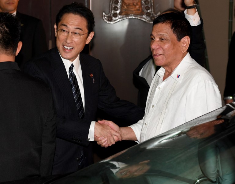 Philippines' President Rodrigo Duterte (R) is welcomed by Japanese Foreign Minister Fumio Kishida (L) prior to their dinner meeting at the entrance of a Japanese restaurant in Tokyo on October 25, 2016.  Duterte is in Japan on a three day visit. / AFP PHOTO / TOSHIFUMI KITAMURA
