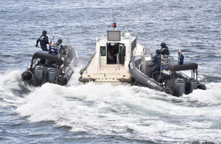 Japan Coast Guard security team display tracking and capture drills by rigid-hulled inflatable boats against an unidentified ship at sea in Yokohama on October 27, 2016 while Philippine President Rodrigo Duterte (not pictured) inspect.   Duterte observed coast guard drills on the final day of a visit to Japan during which tensions in the South China Sea have been a key topic. / AFP PHOTO / AFP PHOTO AND POOL / Kazuhiro NOGI