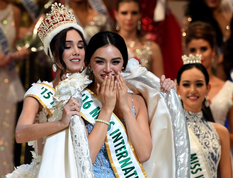 Newly elected 2016 Miss International Kylie Verzosa from Philippines (C) receives her gown from 2015 Miss International Edymar Martinez from Venezuela (L) during the Miss International beauty pageant final in Tokyo on October 27, 2016. / AFP PHOTO / TOSHIFUMI KITAMURA