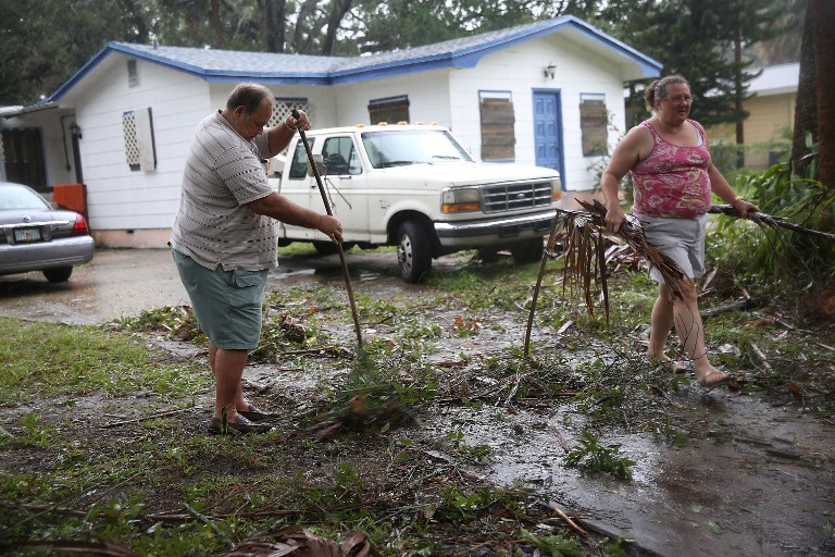 FORT PIERCE, FL - OCTOBER 07: Jim Griggis (L) and Marlin Whaley clean up after Hurricane Matthew passed through the area on October 7, 2016 in Fort Pierce, Florida. The hurricane is expected to make landfall sometime this evening or early in the morning as a possible category 4 storm.   Joe Raedle/Getty Images/AFP