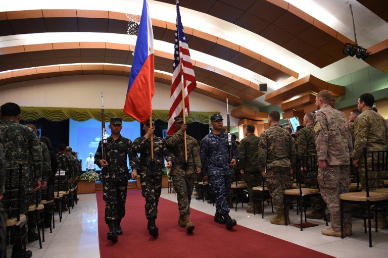 Philippine and US soldiers march with their national flags during the opening ceremony of the annual joint 11-day Balikatan (Shoulder-to-Shoulder) military exercise in Manila on April 4, 2016. US and Philippine troops began major exercises on April 4 as China's state media warned "outsiders" against interfering in tense South China Sea territorial disputes. / AFP PHOTO / TED ALJIBE