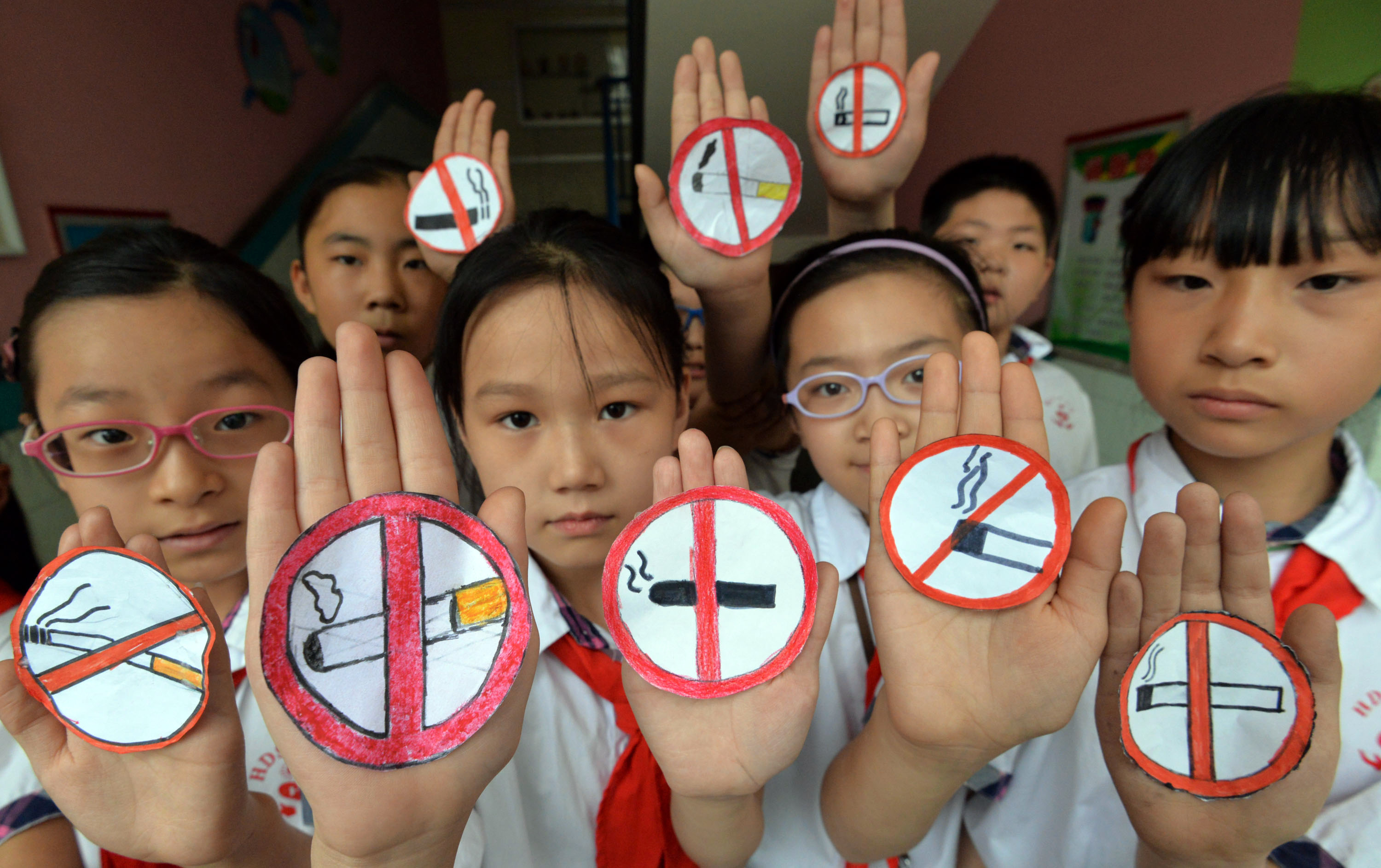 This photo taken on May 30, 2016 shows students wearing masks with no smoking signs to support World No Tobacco Day at a primary school in Handan, northern China's Hebei province.  The slumping output of tobacco products in China has become one of the factors in the country's lowest industrial production rate since the global financial crisis during the first two months of the year. / AFP PHOTO / STR / China OUT