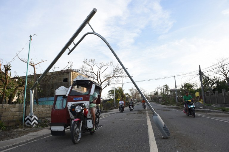 Motorists pass fallen street lights destroyed by super typhoon Haima in Tuguegarao City, Cagayan province, north of Manila on October 21, 2016. Super typhoon Haima, one of the most powerful typhoons to ever hit the Philippines, killed at least eight people on October 20 as ferocious gales and landslides destroyed tens of thousands of homes. / AFP PHOTO / TED ALJIBE