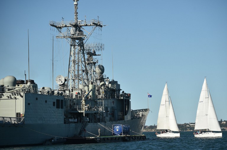 Two yachts sail past the Royal Australian Navy's HMAS Newcastle (FFG 06), an Adelaide-class guided missile frigate, in Sydney Harbour on November 2, 2016. / AFP PHOTO / PETER PARKS