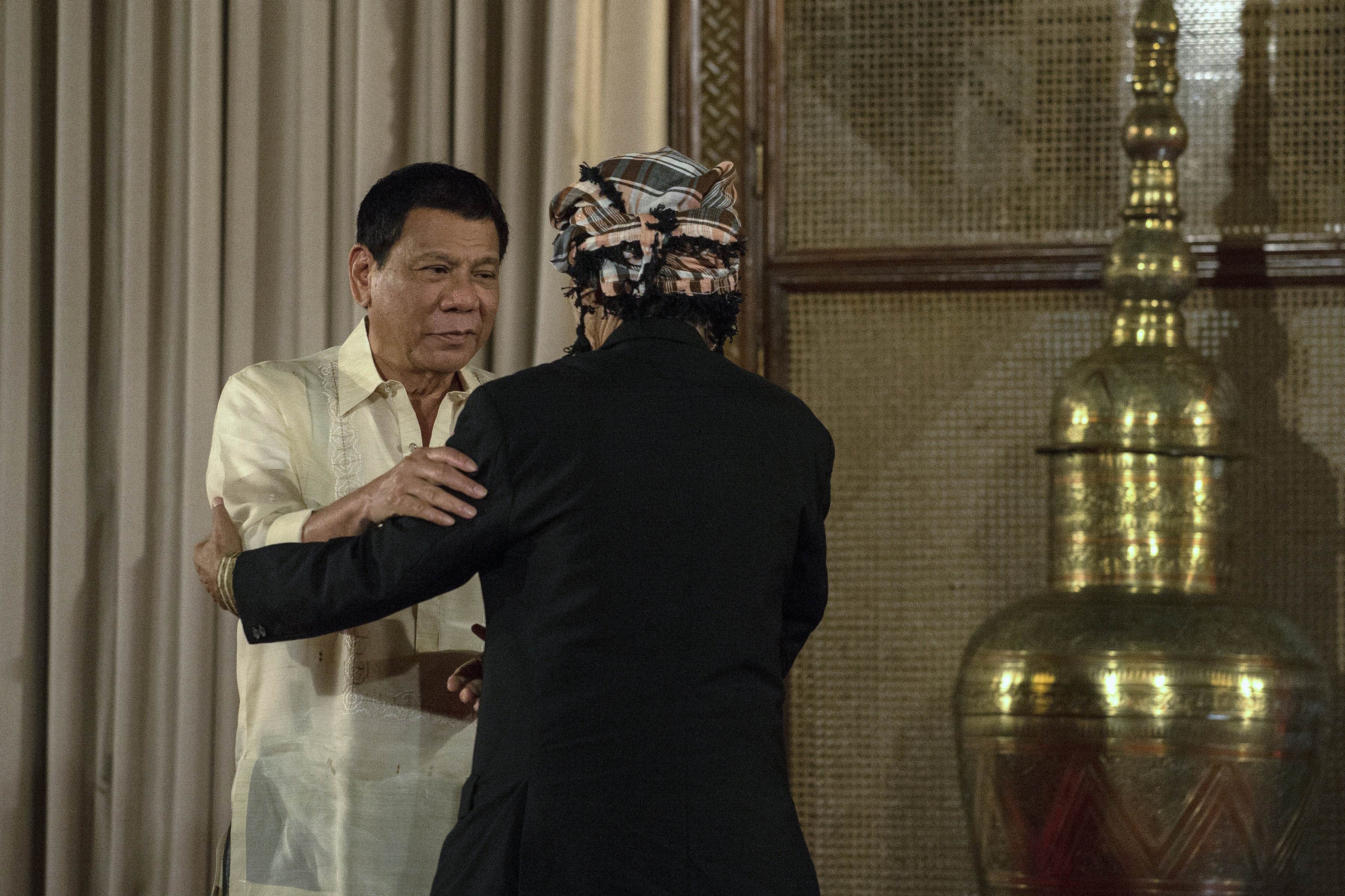 Philippine President Rodrigo Duterte greets Moro National Liberation Front founder Nur Misuari at the Malacanang Palace on November 3, 2016. An influential leader of the Philippines' decades-long Muslim separatist insurgency voiced support November 3 for peace efforts after rebellion charges against him were suspended and he held a surprise meeting with President Rodrigo Duterte. / AFP PHOTO / NOEL CELIS