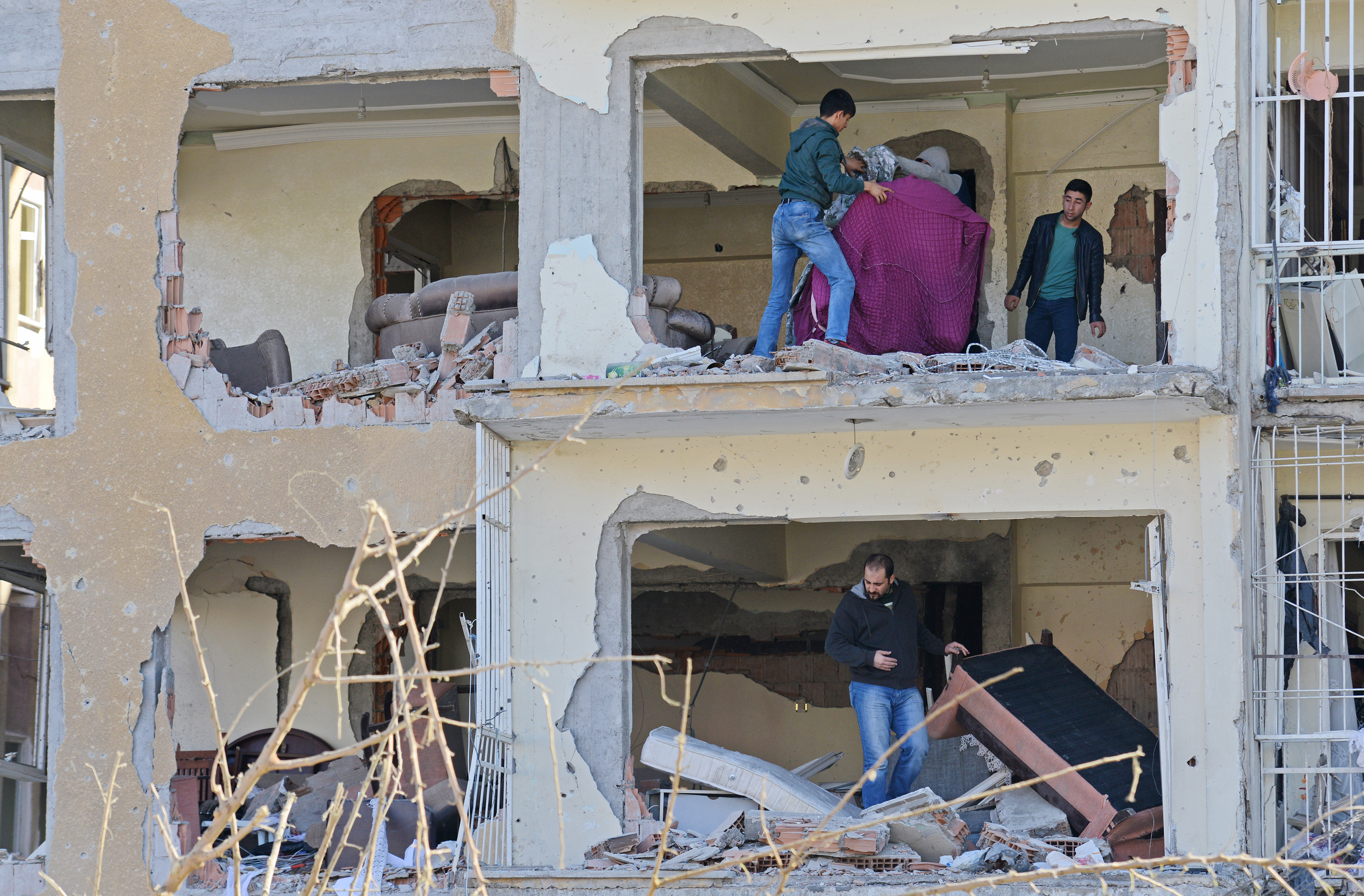 People collect their belongings in a destroyed building on November 5, 2016 a day after a strong blast in the southeastern Turkish city of Diyarbakir.  A news outlet linked to the Islamic State jihadist group said on November 4 that its fighters were behind a bombing that killed nine people in Kurdish-dominated southeastern Turkey, according to US-based monitors. / AFP PHOTO / ILYAS AKENGIN