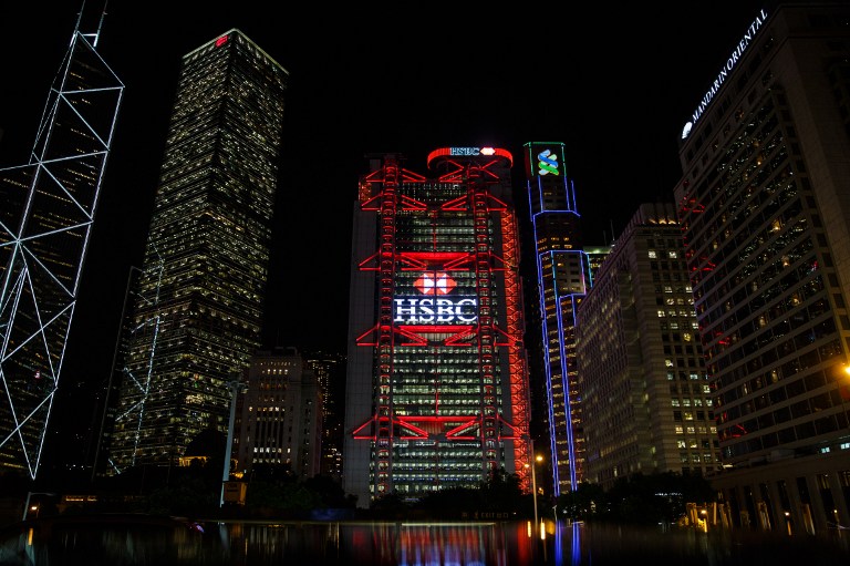 This picture taken on November 4, 2016 shows the illuminated HSBC logo at night on the facade of the HSBC headquarters building in Hong Kong. HSBC said on November 7 its third quarter adjusted pretax profit rose seven percent from a year ago to USD 5.59 billion, beating expectations. / AFP PHOTO / ANTHONY WALLACE