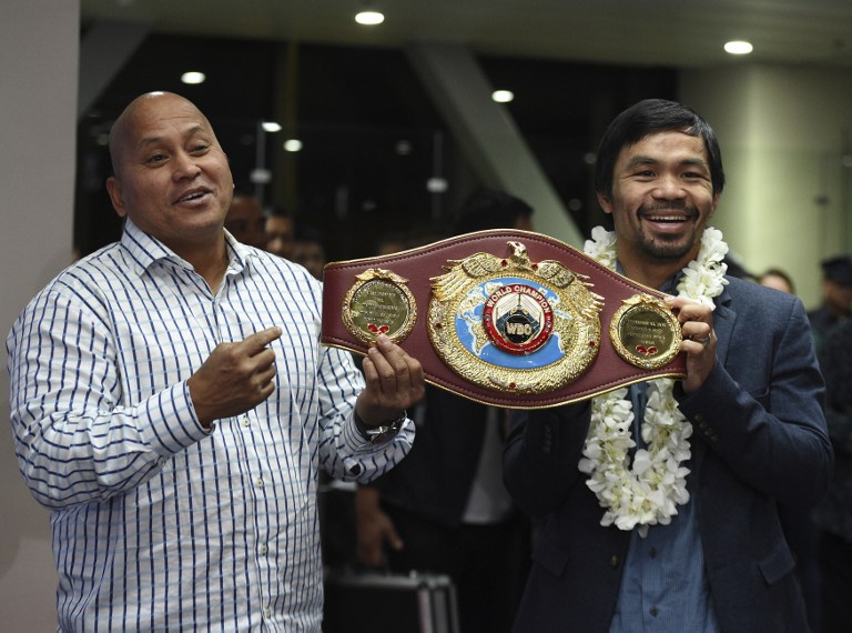 Philippine boxing icon Manny Pacquiao (R) and Chief of National Police Ronald Dela Rosa hold up Pacquiao's welterweight title upon his arrival at the airport in Manila on November 8, 2016, days after reclaiming the World Boxing Organization welterweight title for the third time with a unanimous decision victory over former champion Jesse Vargas. / AFP PHOTO / TED ALJIBE
