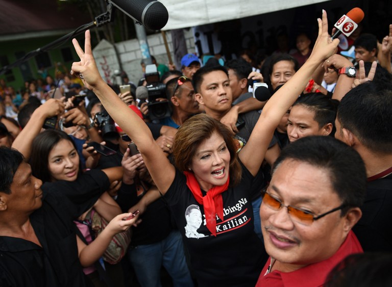 Imee Marcos (C), daughter of the late Philippine dictator Ferdinand Marcos, flashes the "V" sign as she celebrates with supporters during a rally in front of the Supreme Court in Manila on November 8, 2016, after hearing the news of the high court's decision allowing the burial of her late father at the heroes' cemetery.  Marcos can be buried at the national heroes' cemetery, the Supreme Court ruled on November 8 in a hugely controversial verdict that critics warned would whitewash his crimes and divide the nation. / AFP PHOTO / TED ALJIBE