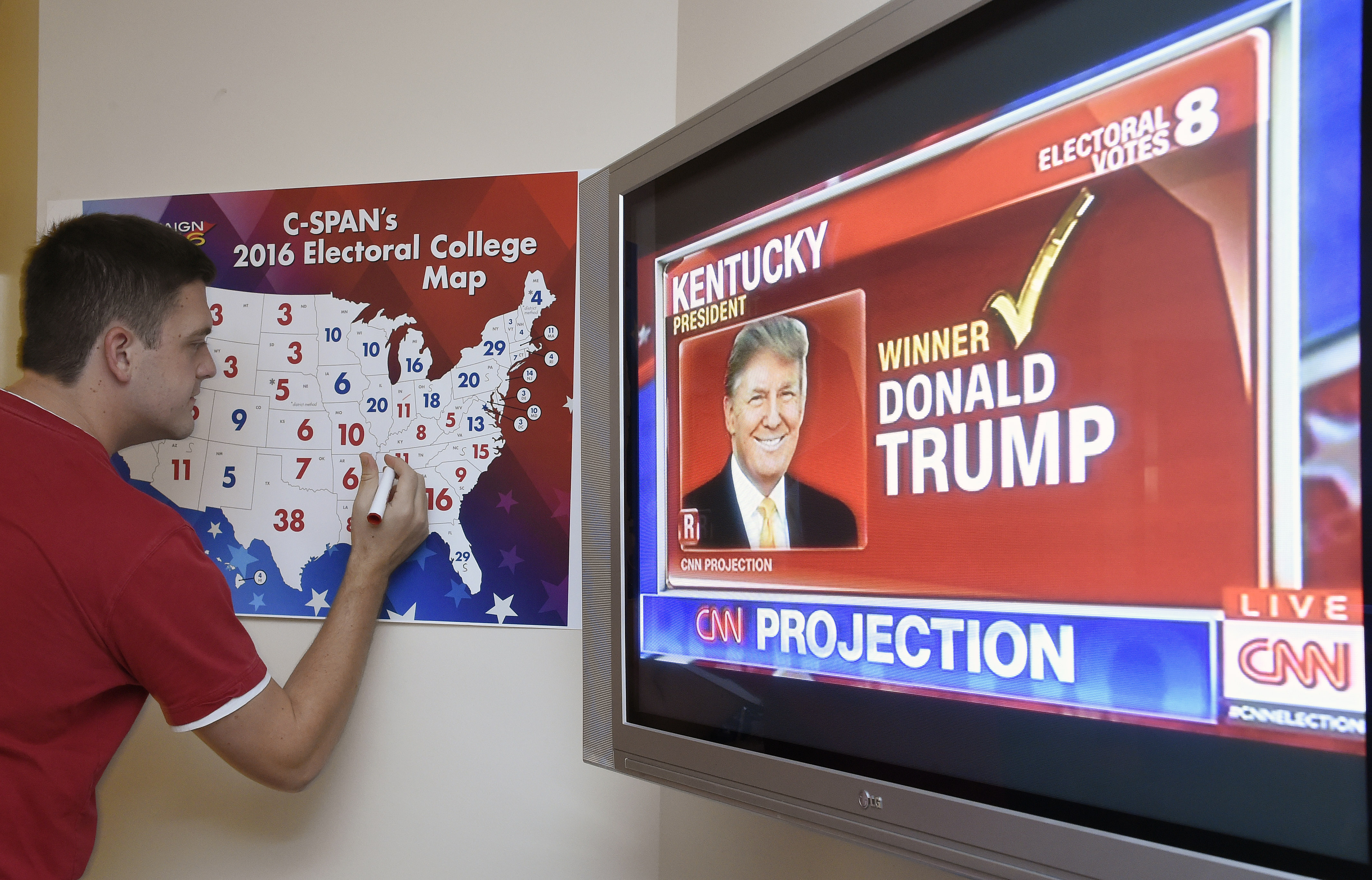 Jake Krupa colors in an electoral map as states are projected for Republican presidential candidate Donald Trump or Democratic Presidential candidate Hillary Clinton at an election watching party in Coconut Grove, Florida, on November 8, 2016. / AFP PHOTO / RHONA WISE