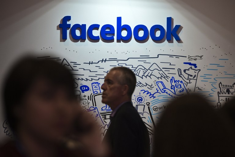 People pass by the stand of Facebook during the Web Summit at Parque das Nacoes, in Lisbon on November 9, 2016. Europe's largest tech event Web Summit will be held at Parque das Nacoes in Lisbon from November 7 to 10, 2016. / AFP PHOTO / PATRICIA DE MELO MOREIRA