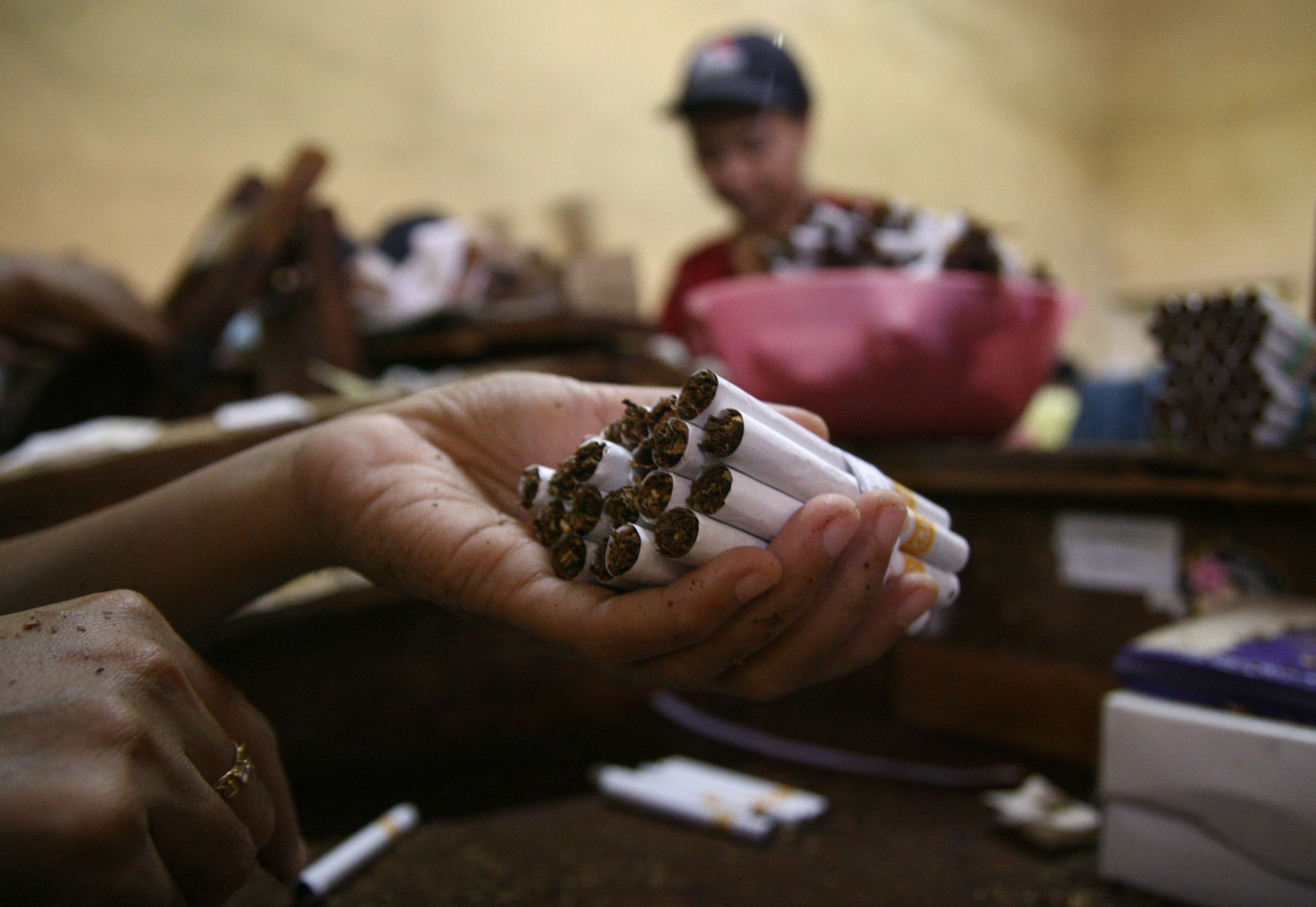 In this photograph taken on January 29, 2013 a person holds cigarettes in a local Indonesian tobacco company employing 600 women workers in Malang located in East Java province. Indonesian President Susilo Bambang Yudhono signed a tobacco regulation on December 24, 2012 in an effort to curb tobacco consumption which has faced staunch opposition from the cigarette lobby. More than 237,000 people work in the countrys tobacco industry, producing some 190 billion cigarettes, according to data from the World Health Organization.  AFP PHOTO / AMAN ROCHMAN / AFP PHOTO / AMAN ROCHMAN