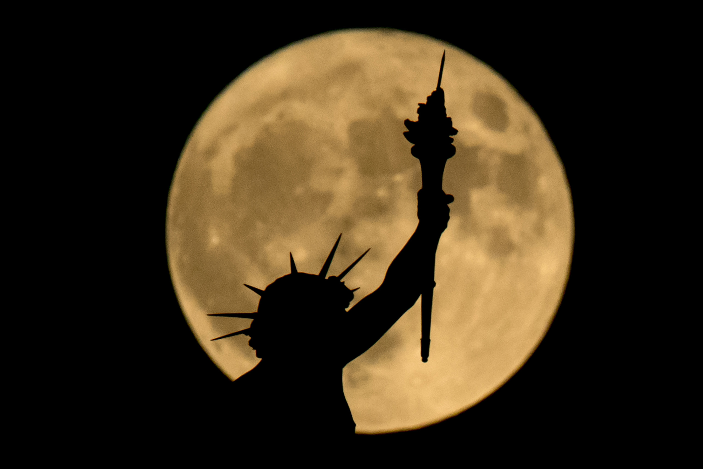 The supermoon is seen above a statue at the top of the Nature and History Museum on November 14, 2016 in Vienna, Austria.  The unusually big and bright moon appeared at its most impressive as night fell over Asia, but astronomy enthusiasts will be able to see Earth's satellite loom large anywhere in the world shortly after sunset.  / AFP PHOTO / JOE KLAMAR