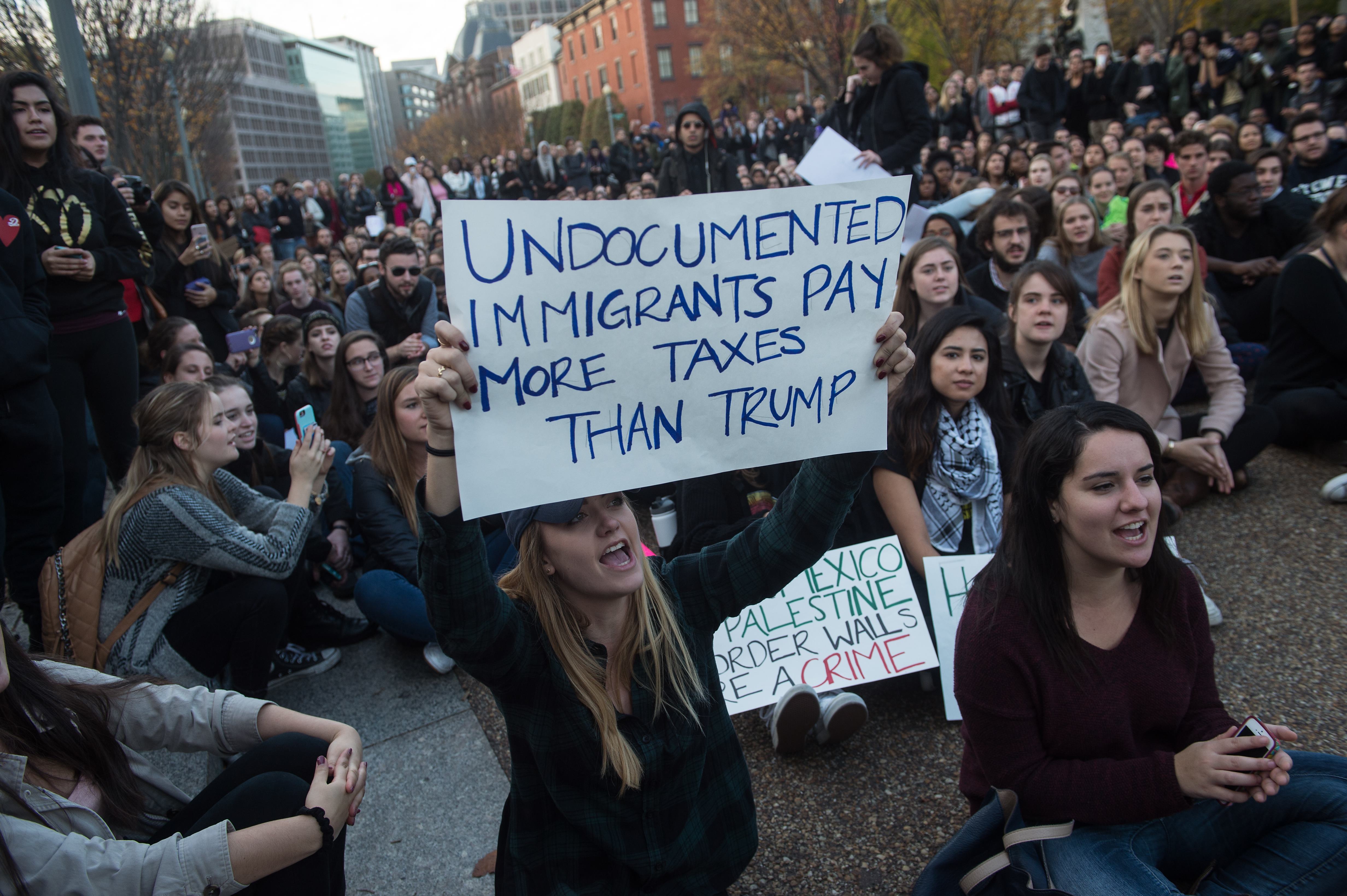 A student from George Washington University holds a sign in front of the White House in Washington, DC, on November 15, 2016 as students protest the election of US President-elect Donald Trump. / AFP PHOTO / NICHOLAS KAMM