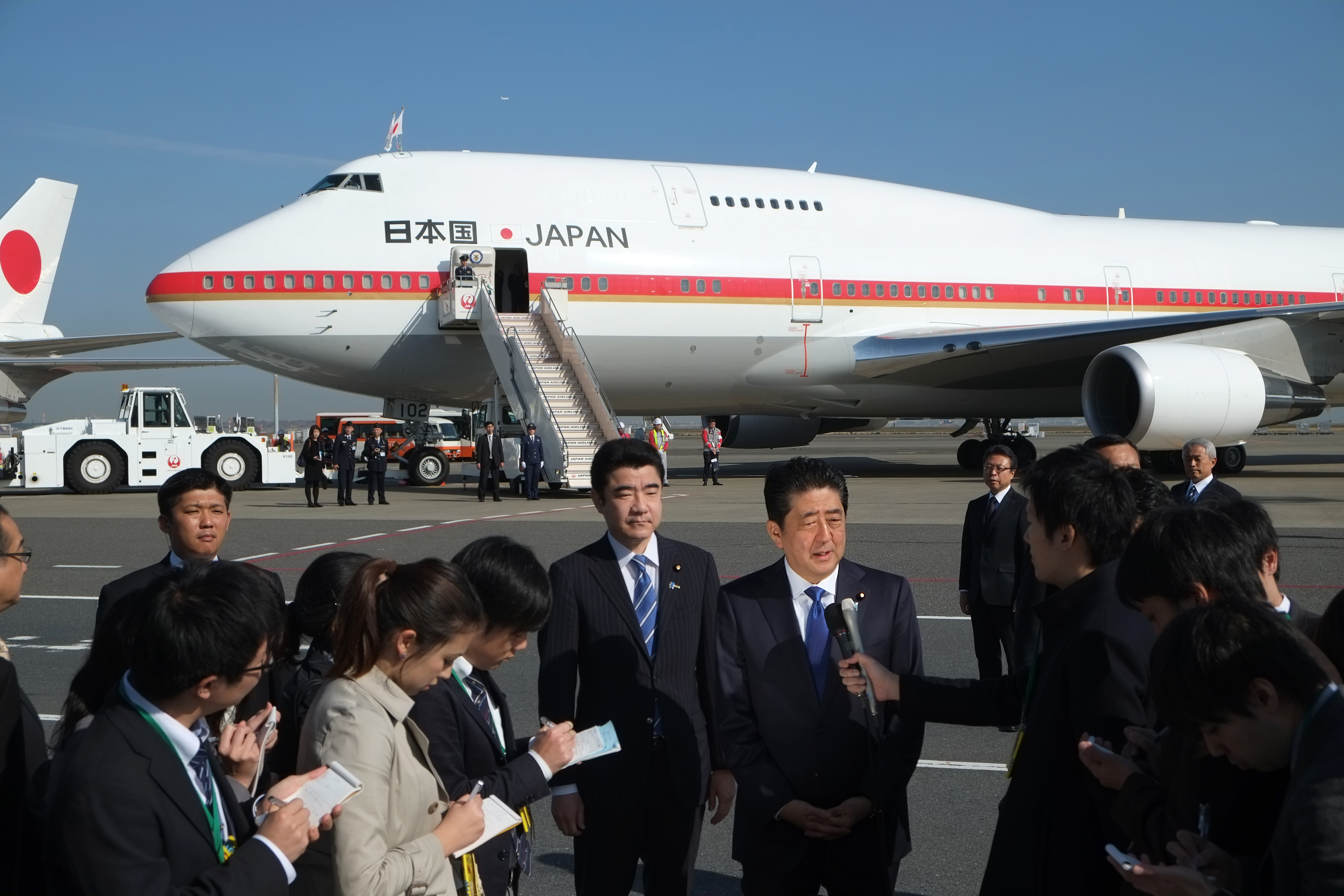 Japan's Prime Minister Shinzo Abe (C) speaks to reporters prior to boarding a government plane at Tokyo's Haneda Airport on November 17, 2016.  Abe headed to New York on November 17 for talks with Donald Trump, the first leader to meet with the president-elect whose campaign pledges provoked anxiety over US foreign policy. / AFP PHOTO / KAZUHIRO NOGI