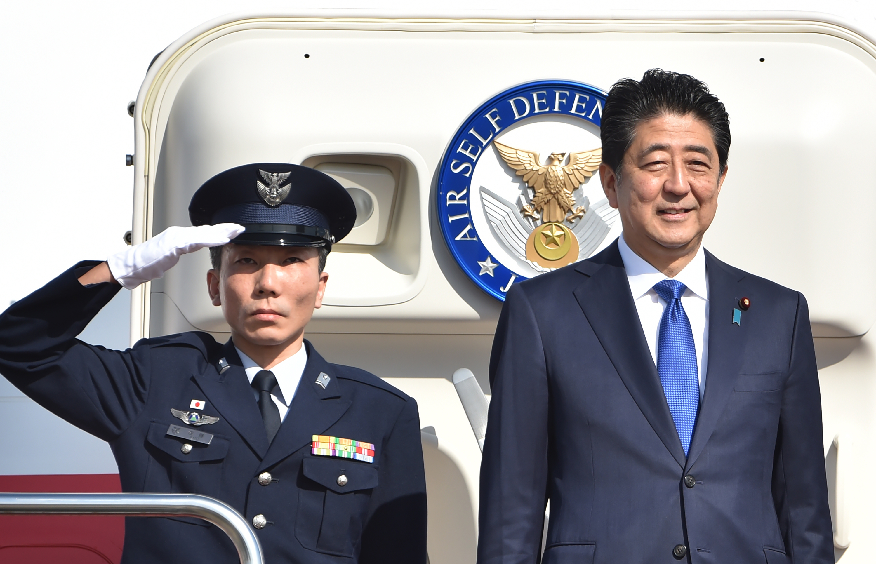 Japan's Prime Minister Shinzo Abe (R) leaves Tokyo's Haneda Airport on November 17, 2016.  Abe headed to New York on November 17 for talks with Donald Trump, the first leader to meet with the president-elect whose campaign pledges provoked anxiety over US foreign policy. / AFP PHOTO / KAZUHIRO NOGI