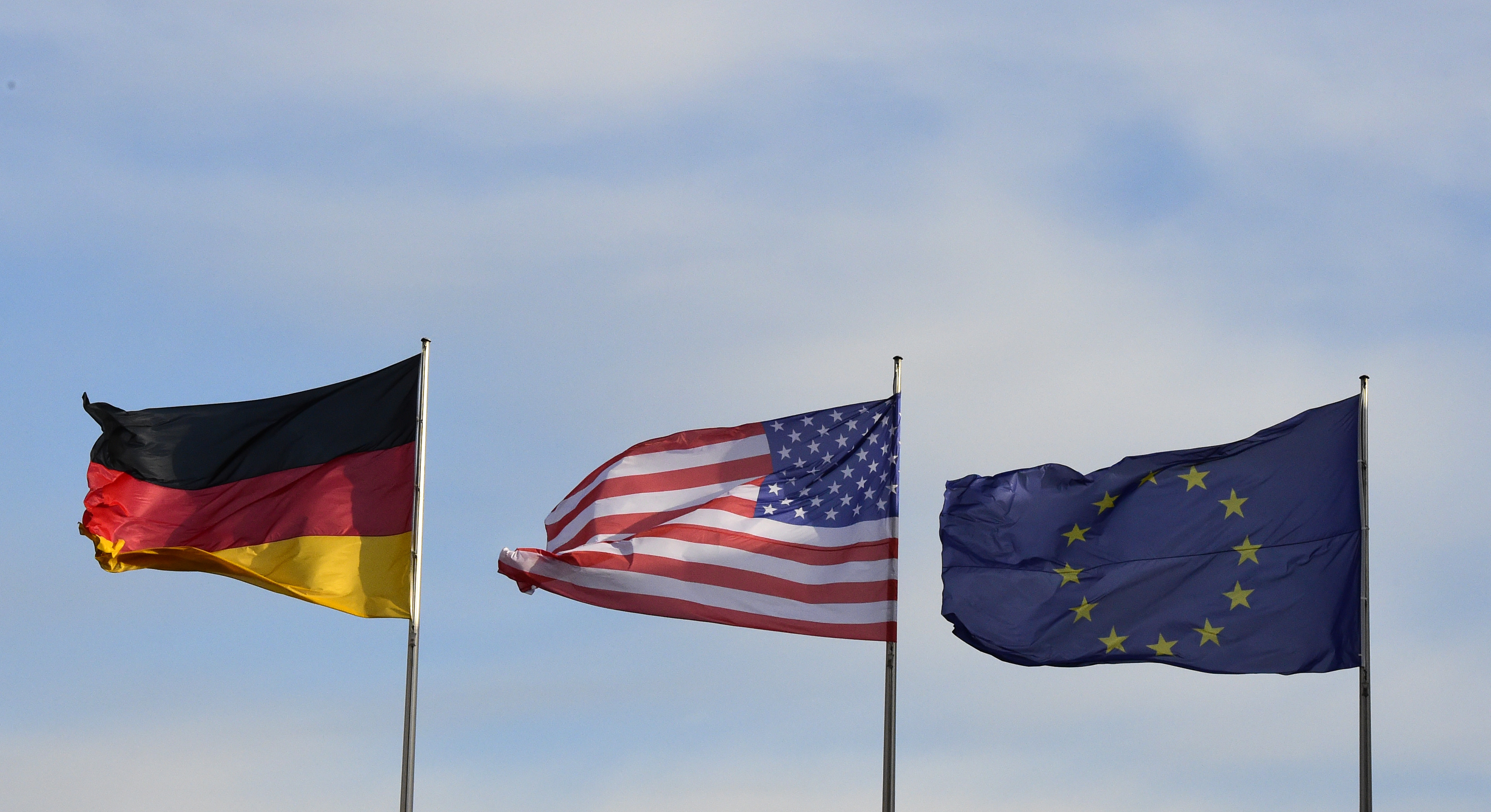 The flags of Germany (L), the US and EU flutter at the Chancellery in Berlin, where the German Chancellor is expected to meet the US President paying his farewell visit to the German capital on November 17, 2016. US President Barack Obama is to meet German Chancellor Angela Merkel, widely seen as the new standard bearer of liberal democracy since the election of Donald Trump. On the last leg of his final European tour as president, Obama will underline shared values, try to ease fears about the future of the transatlantic partnership and thank Merkel for her friendship during his two terms, White House officials said. / AFP PHOTO / TOBIAS SCHWARZ