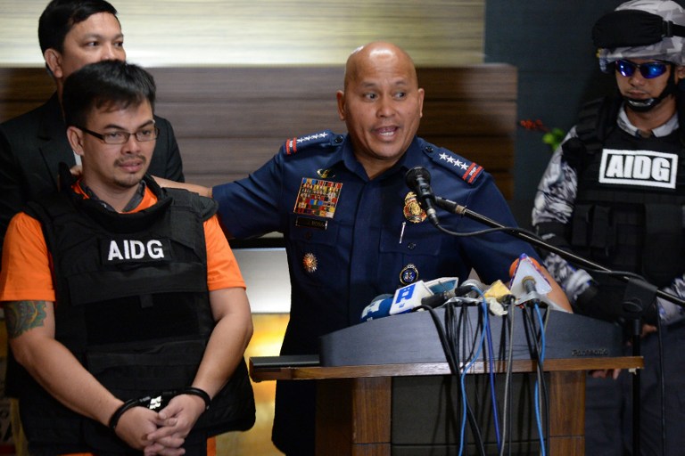 Philippine National Police (PNP) chief Director General Ronald dela Rosa (R) gestures as he presents Kerwin Espinosa, son of the late mayor Rolando Espinosa, to members of the media at the police headquarters in Manila on November 18, 2016 after Espinosa arrived from the United Arab Emirates. Kerwin was arrested in the United Arab Emirates last month and will face drug trafficking charges. His father Rolando, a mayor President Rodrigo Duterte named as being involved in the illegal drug trade, was shot dead in jail on November 5. / AFP PHOTO / TED ALJIBE