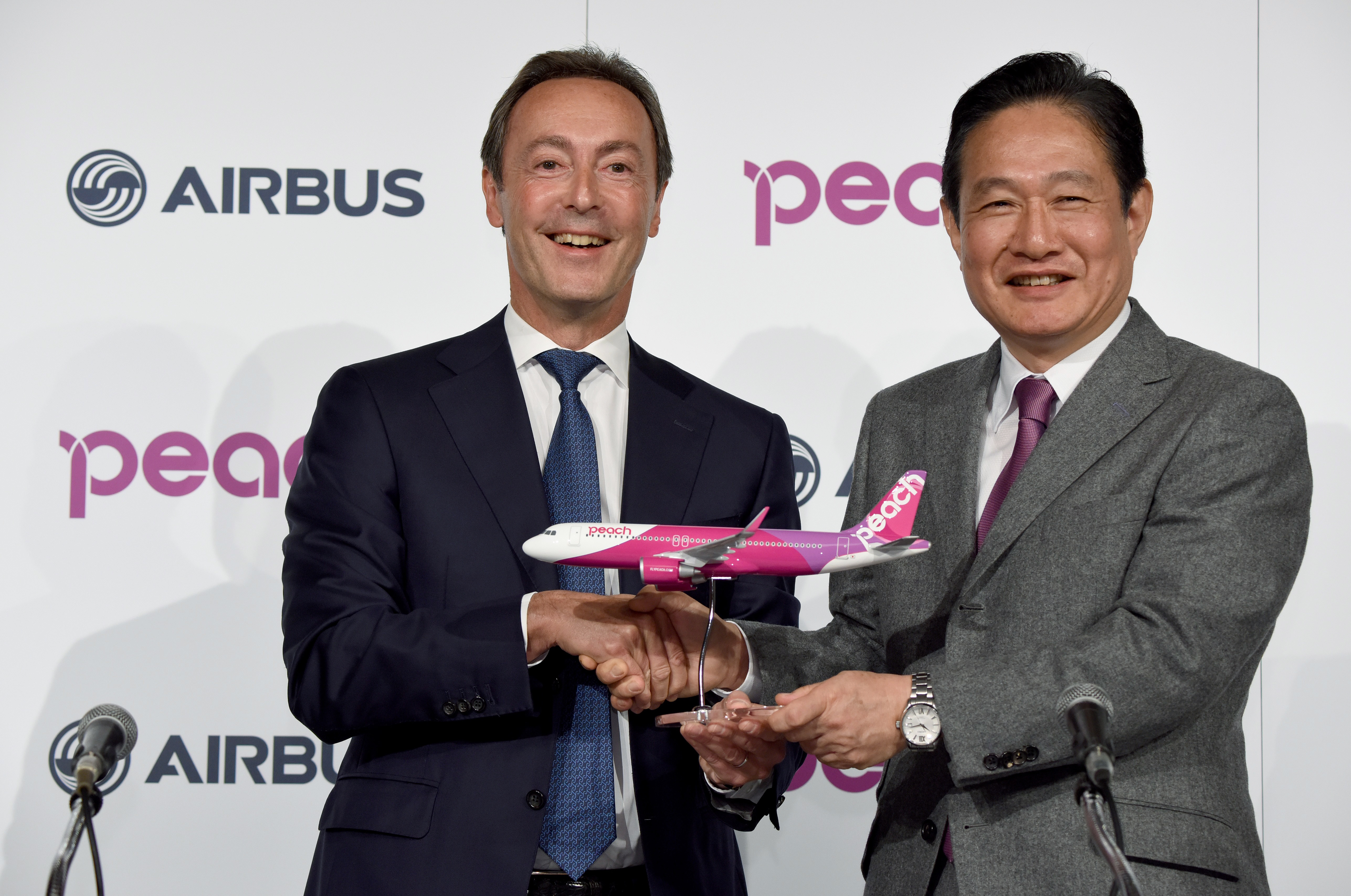 Airbus ECO Fabrice Bregier (L) shakes hands with CEO of Japan's low cost carrier Peach Aviation Shinichi Inoue during a joint press conference in Tokyo on November 18, 2016.  Japanese low-cost carrier Peach Aviation said on November 18 it would buy 13 Airbus aircraft valued at almost $1.4 billion as part of its expansion plans to cash in on a pick-up in demand for air travel in the country. / AFP PHOTO / TORU YAMANAKA