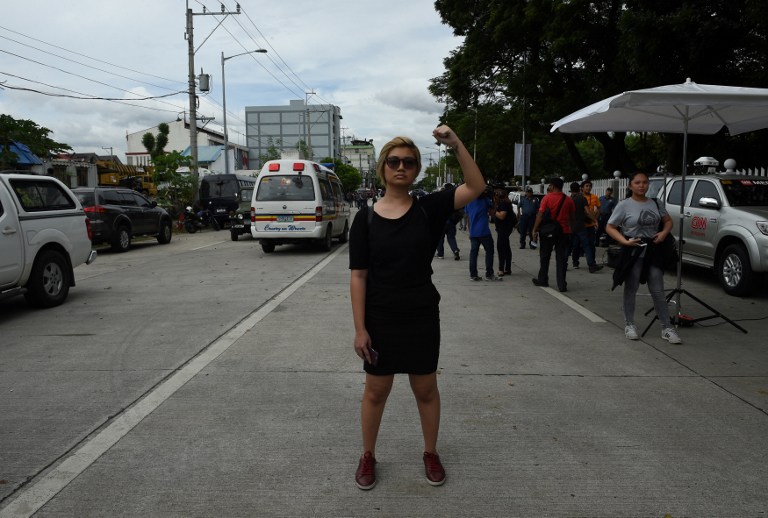 A lone anti-Marcos protestor raises clinch fist during a protest in front of the gates of the heroes' cemetery while the late dictator Ferdinand Marcos was being given a heroe's burial in Manila on November 18, 2016.  Ex-Philippine dictator Ferdinand Marcos was buried at the national heroe's cemetery in a secretive ceremony, outraging opponents who said it whitewashed his brutal rule and tainted the famous 1986 "People Power" revolution that toppled him. / AFP PHOTO / TED ALJIBE