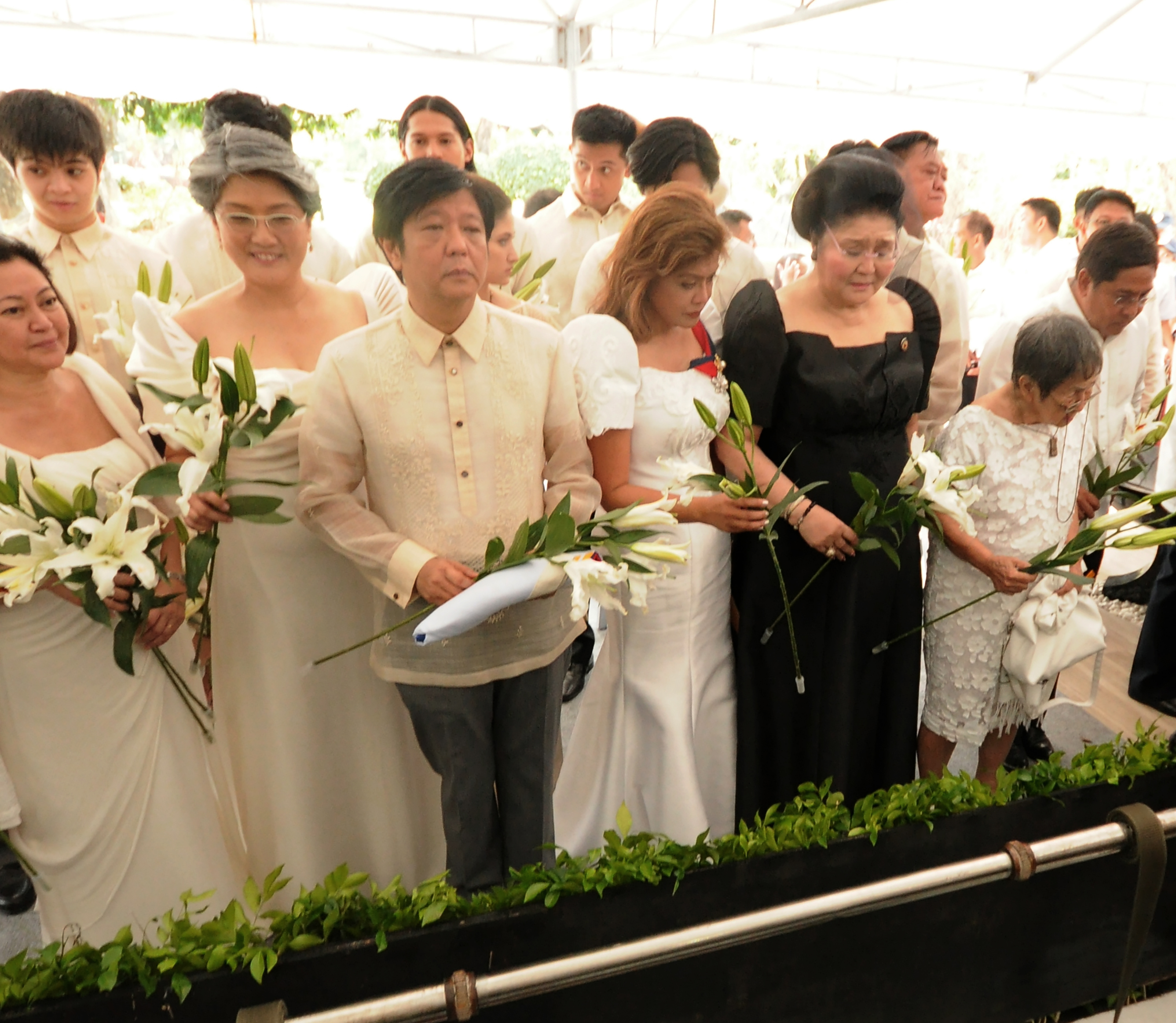 This handout photo taken on November 18, 2016 and released by the office of Governor Imee Marcos shows former first lady Imelda Marcos (in black) prepare to offer flowers with son Bongbong (3rd L), daughters Governor Imee (3rd R) and Irene (2nd L) during the burial of the late President Ferdinand Marcos at the national heroes' cemetery in Manila.  Marcos was buried at the national heroes' cemetery in a secretive ceremony November 18, outraging opponents   / AFP PHOTO / Office of Governor Imee Marcos / HO