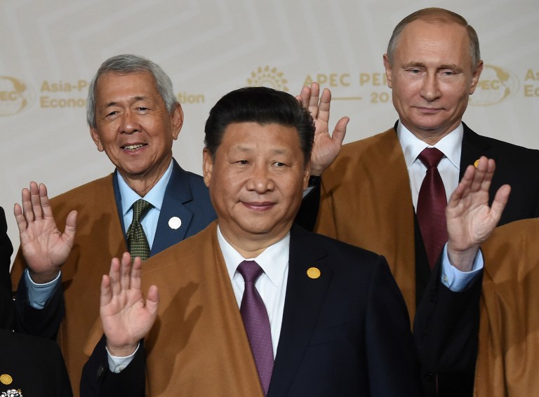 (L to R) Philippine Foreign Secretary Perfecto Yasay, China's President Xi Jinping and Russia's President Vladimir Putin take part in the traditional "family photo" on the final day of the Asia-Pacific Economic Cooperation (APEC) Summit at the Lima Convention Centre in Lima on November 20, 2016. Asia-Pacific leaders were expected to send a strong message in defense of free trade on November 20 as they wrap up a summit that has been overshadowed by US President-elect Donald Trump's protectionism.  / AFP PHOTO / Martin BERNETTI