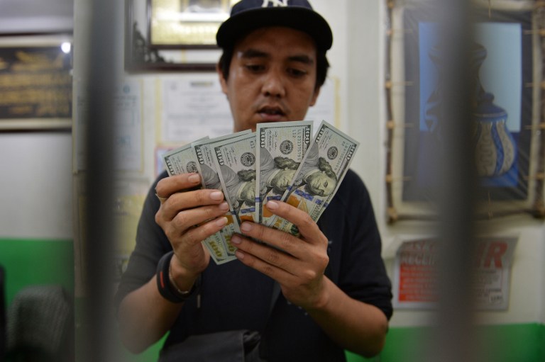 A money exchange store employee counts US dollar notes in Manila on November 24, 2016.  The Philippine peso fell to its lowest level against the dollar in eight years as it breached the P50 to 1 USD mark on November 24. / AFP PHOTO / TED ALJIBE