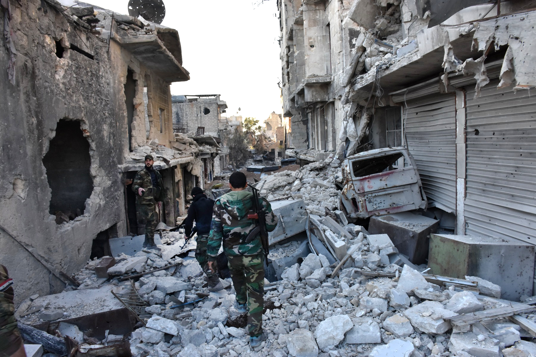 Syrian pro-government forces walk amidst heavy destruction in Aleppo's Bustan al-Basha neighbourhood on November 28, 2016, during their assault to retake the entire northern city from rebel fighters. In a major breakthrough in the push to retake the whole city, regime forces captured six rebel-held districts of eastern Aleppo over the weekend, including Masaken Hanano, the biggest of those in eastern Aleppo.    / AFP PHOTO / GEORGE OURFALIAN