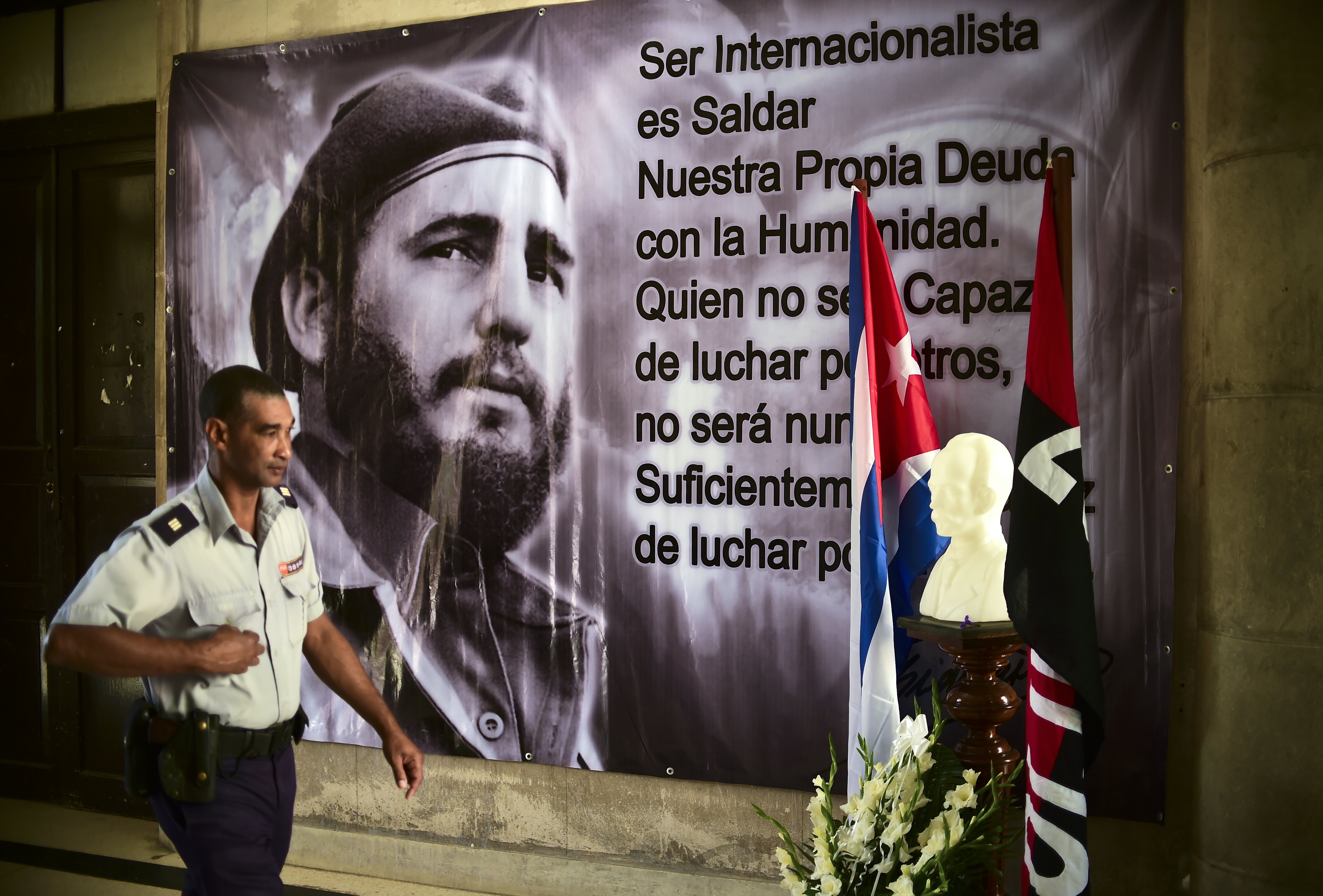 A police officer passes by a large portrait of late Cuban revolutionary leader Fidel Castro at the City Hall of the Guanabacoa municipality in Havana, on November 28, 2016.  Hundreds of thousands of Cubans flocked to Havana's iconic Revolution Square in a tearful and nostalgic tribute to Fidel Castro on Monday, launching a week-long farewell to the divisive Cold War icon. / AFP PHOTO / RONALDO SCHEMIDT
