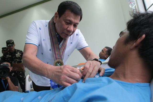 President Duterte pins a medal to a wounded soldier