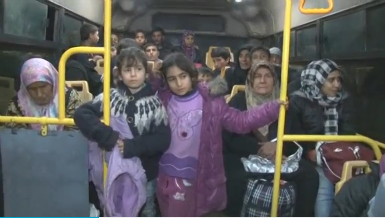 Fleeing residents were temporarily transported by green government buses. (Photo courtesy of Reuters video clip)