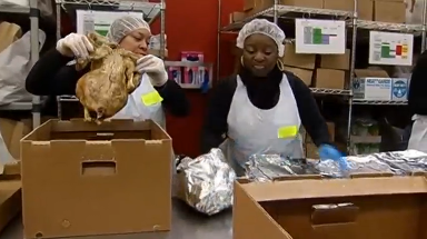 Volunteer placing turkey on a foil. (Photo courtesy of Reuters video file)