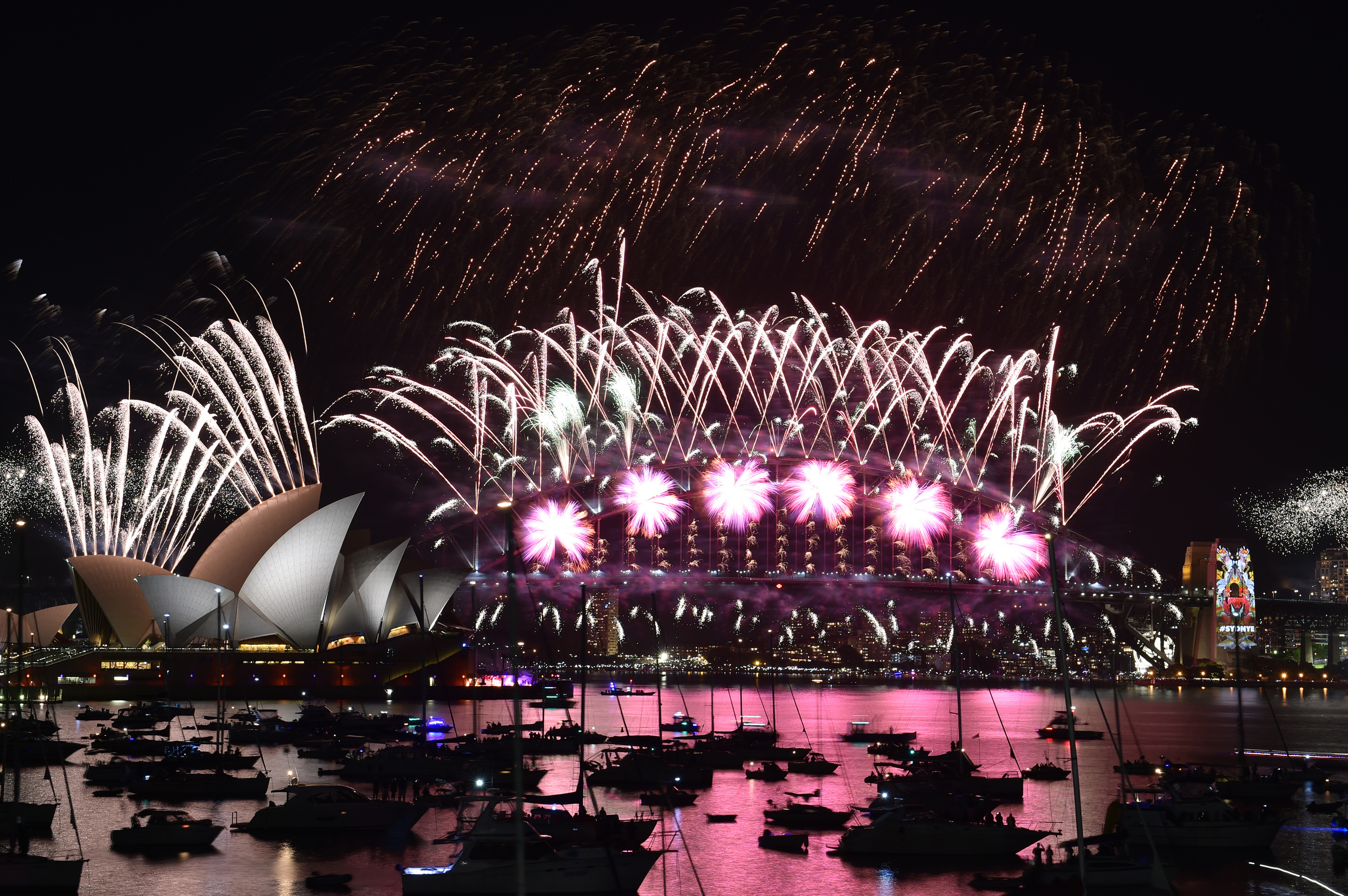 Fireworks light up the sky over Sydney's Opera House (L) and Harbour Bridge during New Year celebrations in Sydney on January 1, 2016.  AFP PHOTO / Saeed KHAN / AFP PHOTO / SAEED KHAN