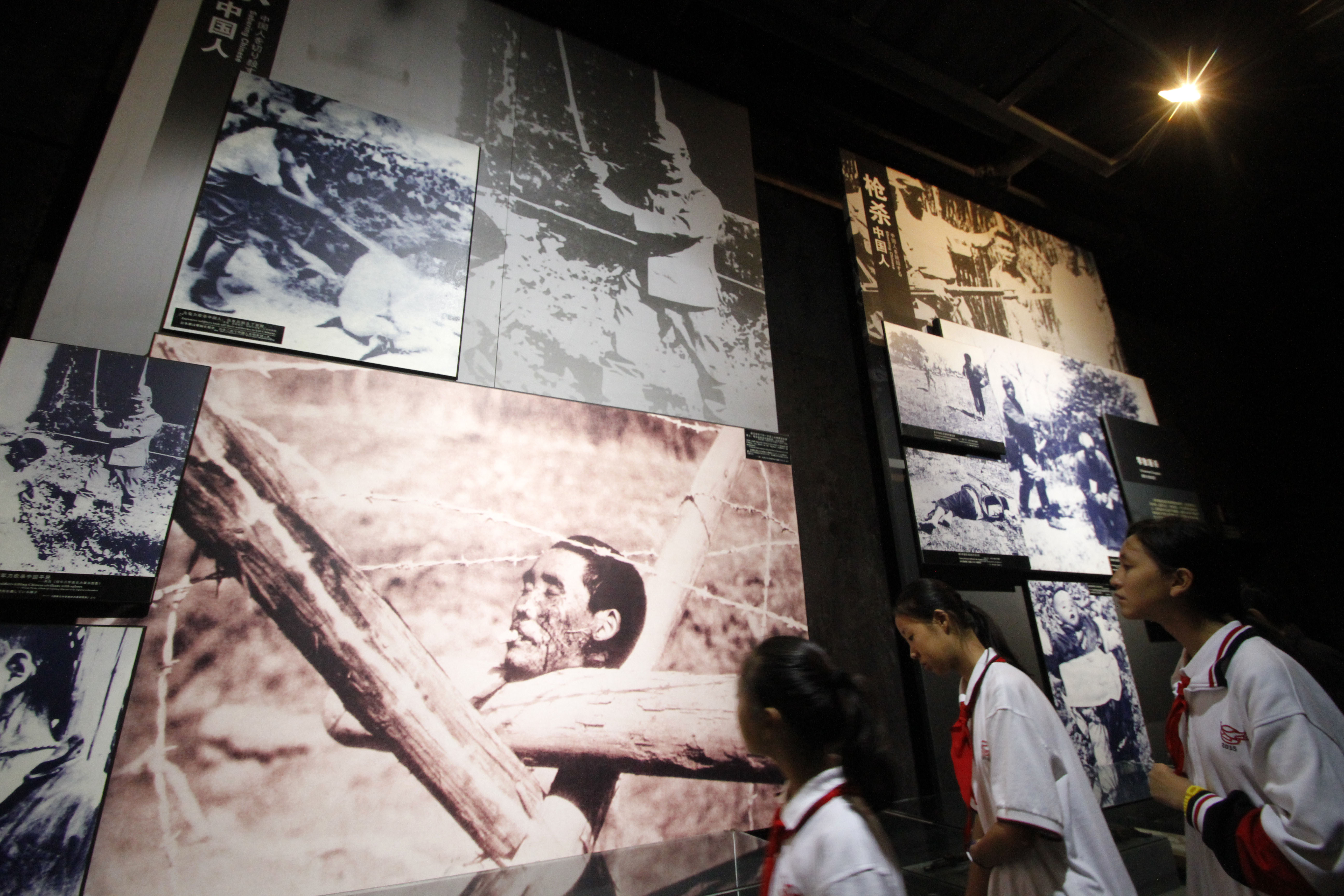 Visiting schoolchildren look at photos on display at the Nanjing Massacre Memorial Hall in Nanjing on October 10, 2015.  Japan on October 10 lashed out at UNESCO's decision to inscribe documents related to the Nanjing massacre in its Memory of the World register, describing it as "extremely regrettable" and calling for the process to be reformed.     CHINA OUT      AFP PHOTO / AFP PHOTO / STR
