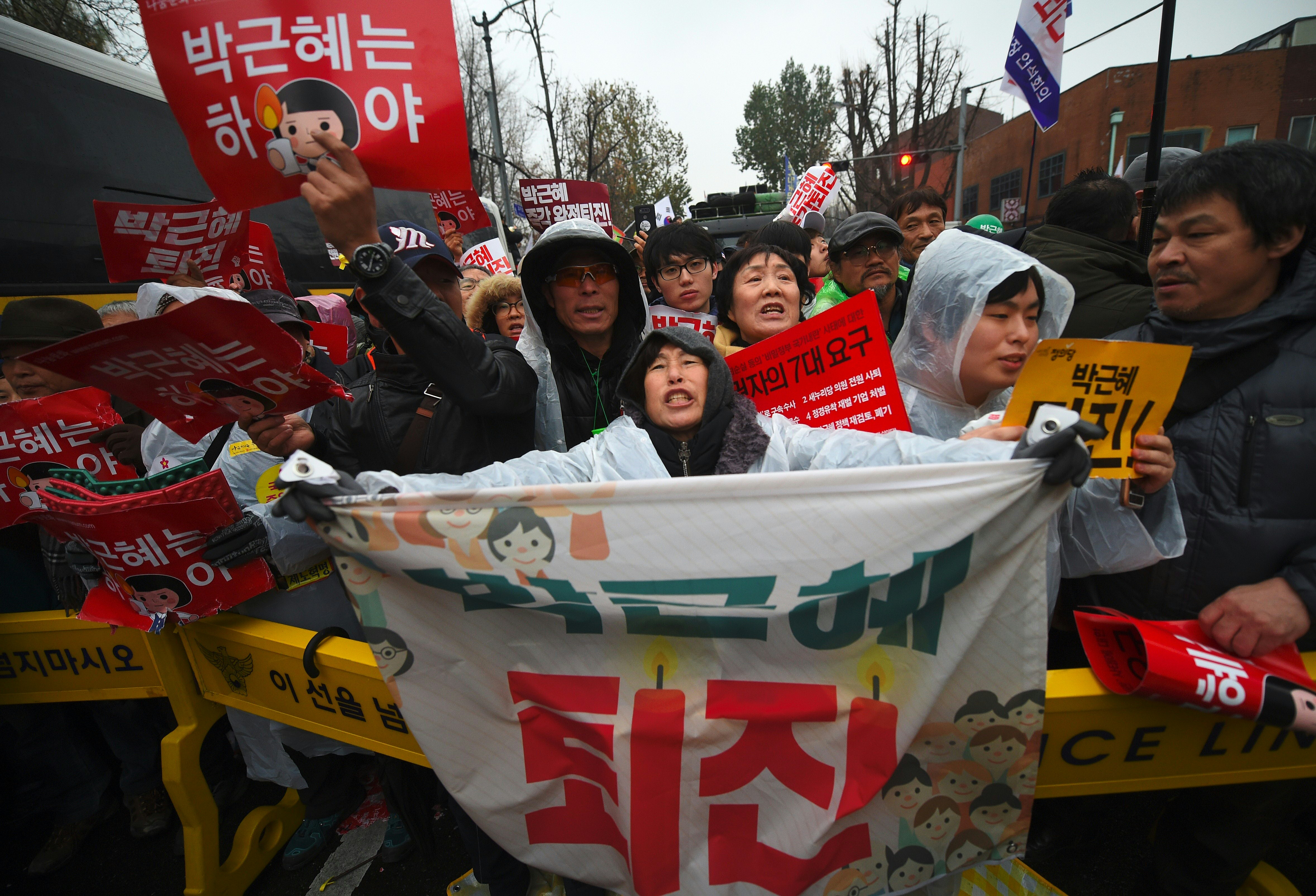 Protesters shout slogans as they march toward the presidential Blue House to press their demand for the resignation of South Korea's President Park Geun-Hye in central Seoul on November 26, 2016. Tens of thousands of protesters braved sleet and freezing temperatures in Seoul on November 26 to demand Park resign over a corruption scandal or face impeachment. / AFP PHOTO / JUNG Yeon-Je