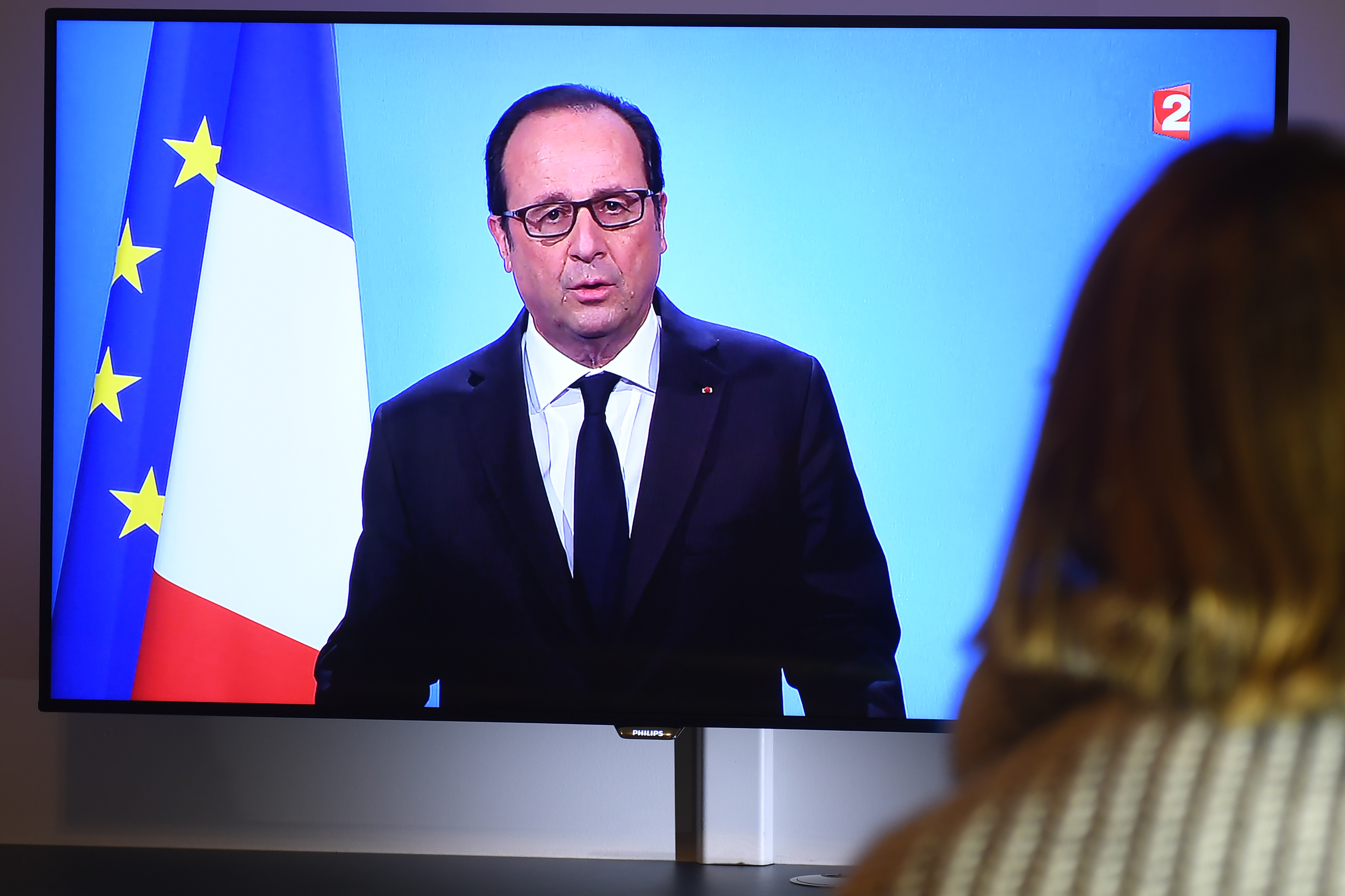 A person watches on December 1, 2016 a TV screen showing French President Francois Hollande announcing his renouncement to run for the next French presidential elections. Francois Hollande dramatically announced he would not seek re-election next year as he bowed to historic low approval ratings after a troubled five years in power. The withdrawal means the 62-year-old Socialist leader is the first president of France's fifth republic, founded in 1958, to step aside after only one term. / AFP PHOTO / DAMIEN MEYER